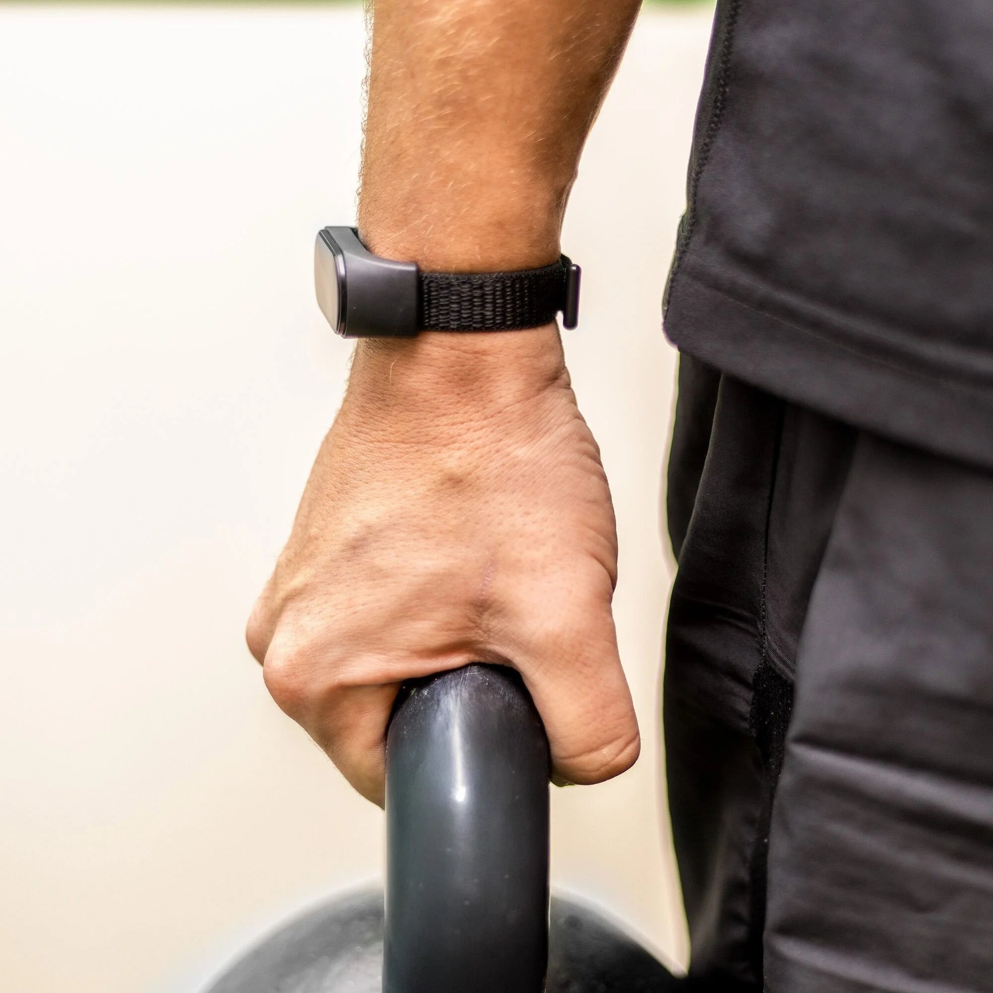 Eine Person hält eine graue Stange. Eine schwarze Uhr befindet sich am Handgelenk. Die Person trägt ein schwarzes Hemd.
