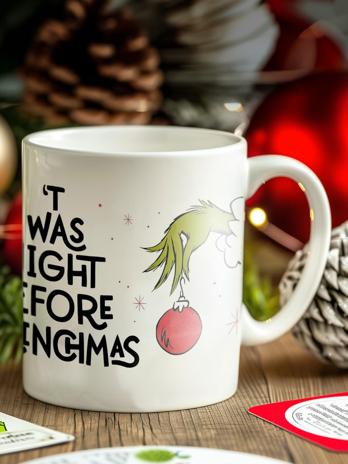 Eine weiße Tasse mit Grinch-Kunst. Der Text lautet: „Ich hatte vor Weihnachten Recht“. Ein roter Schmuck hängt an der Hand des Grinch.