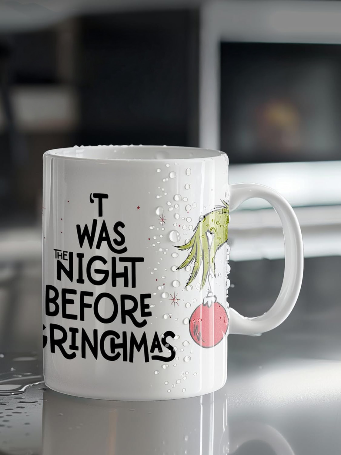 Weiße Tasse mit Grinch-Design, Text lautet 'T was the night before Grinchmas'. Rote Verzierung. Wassertropfen auf der Tasse.