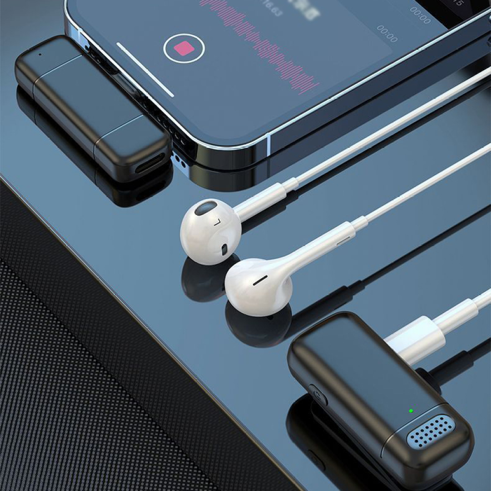 Smartphone mit Aufnahme-App, weiße Kopfhörer und schwarze Audiorekorder liegen auf einer spiegelnden Oberfläche. Zubehör sichtbar.