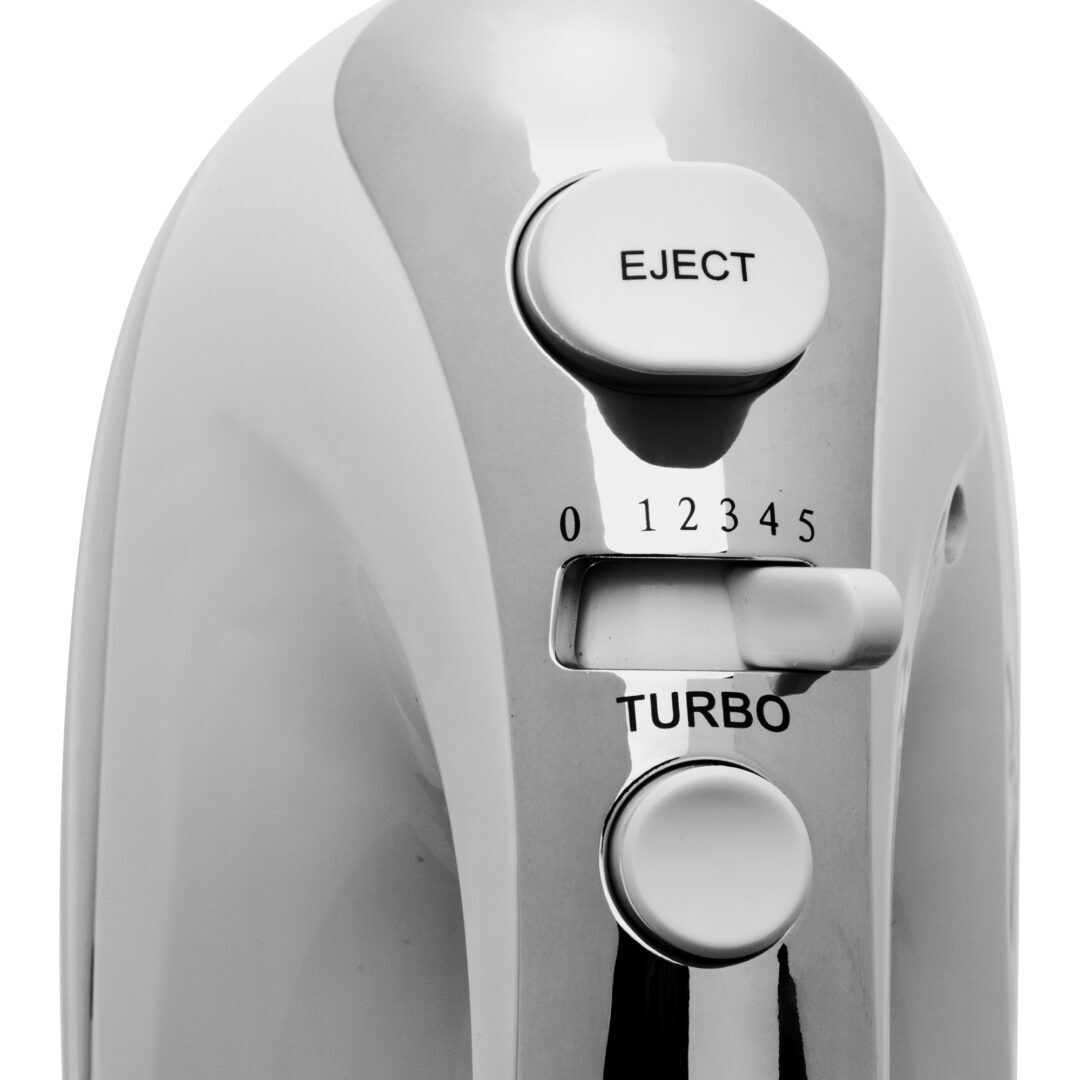 Primer plano de una batidora de mano blanca y plateada. Incluye un botón de expulsión, ajustes de velocidad 0-5, un botón turbo y un dial.