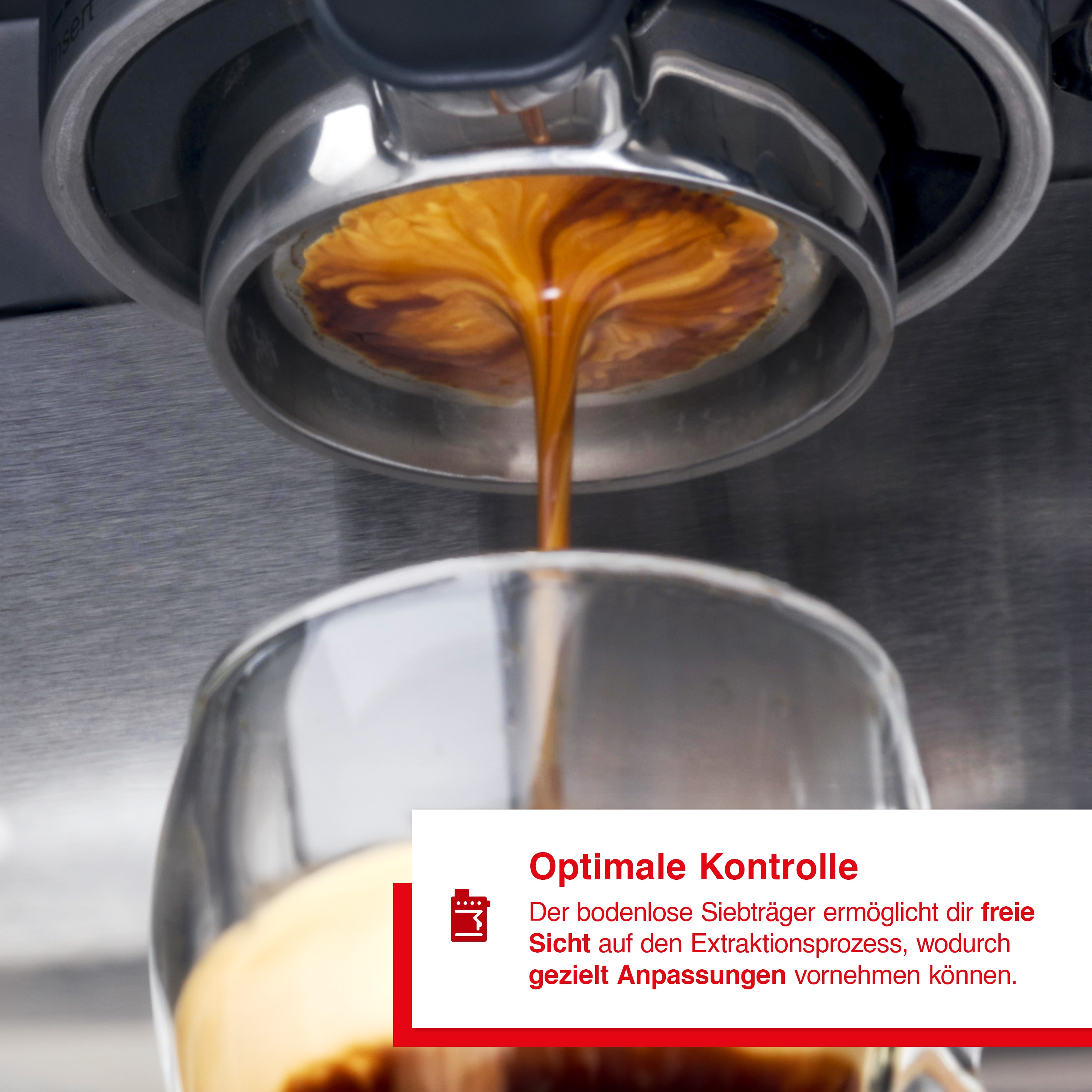 Nahaufnahme einer Espressomaschine, die Kaffee in ein Glas gießt. Der Kaffeestrahl und die Maschine sind im Fokus. Text ist sichtbar.