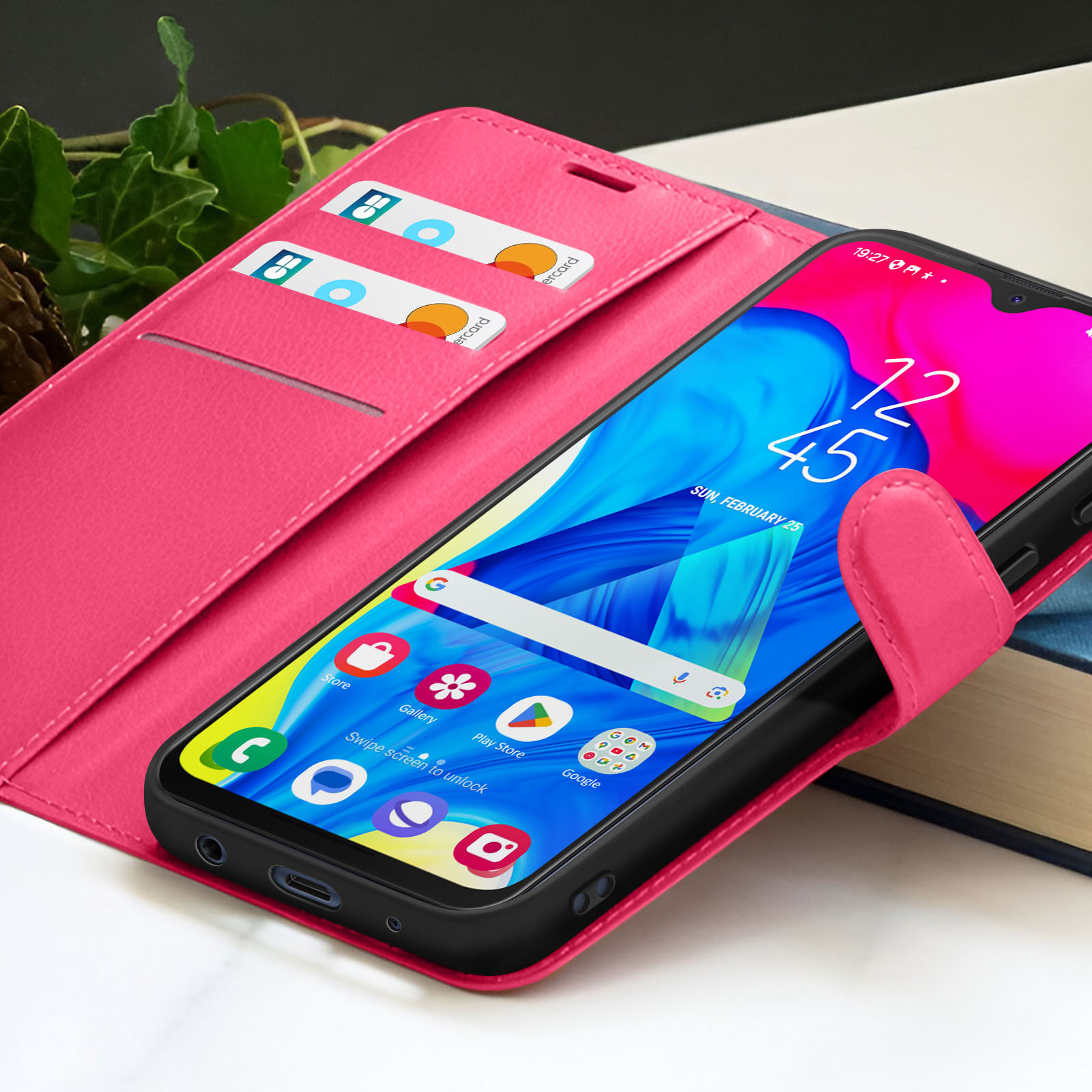 Een smartphone in een roze hoesje met creditcards. Het scherm toont tijd en app-iconen tegen een blauwpaarse achtergrond.