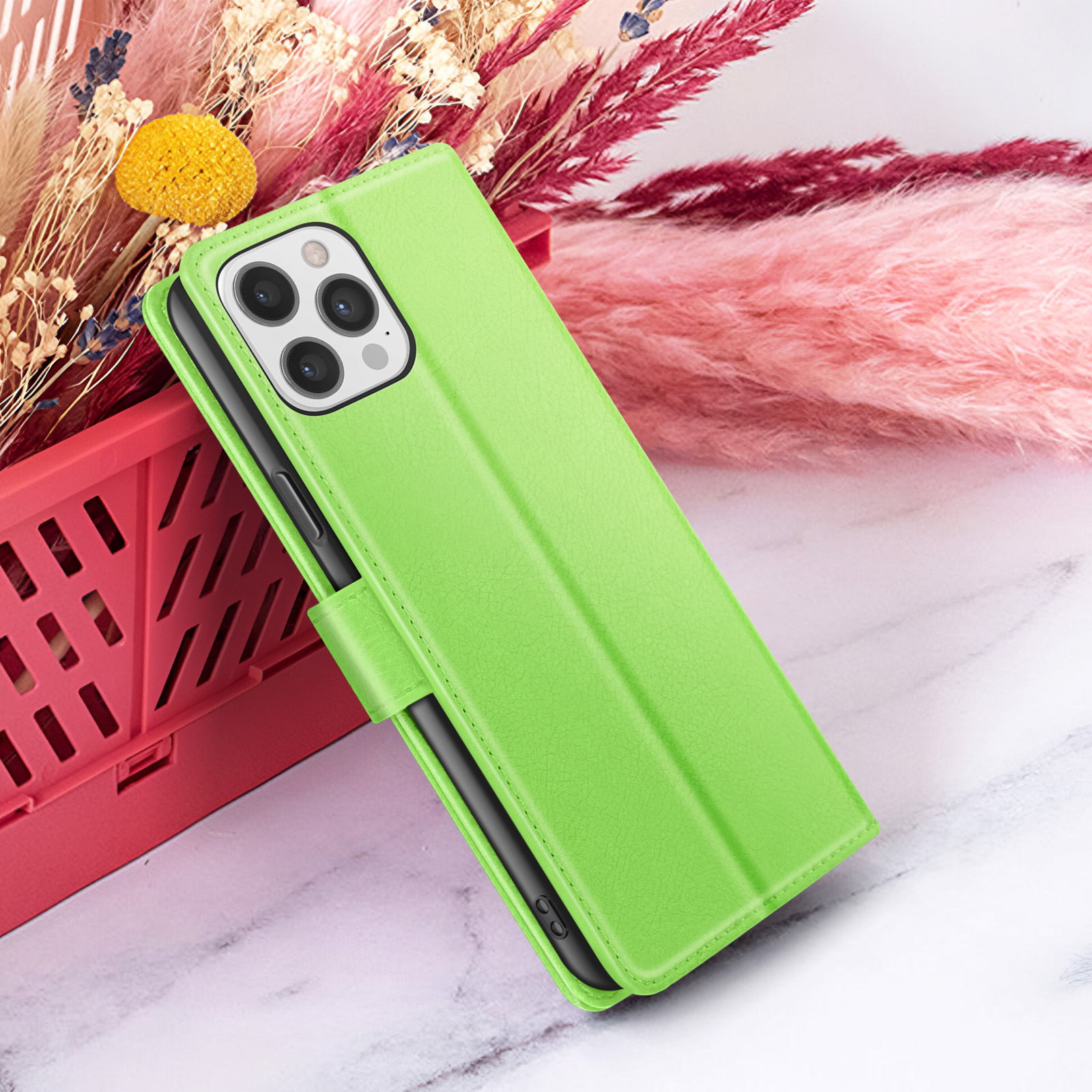 Un étui de téléphone vert avec plusieurs caméras est affiché. Des fleurs roses et blanches sont en arrière-plan. L'étui est ouvert.