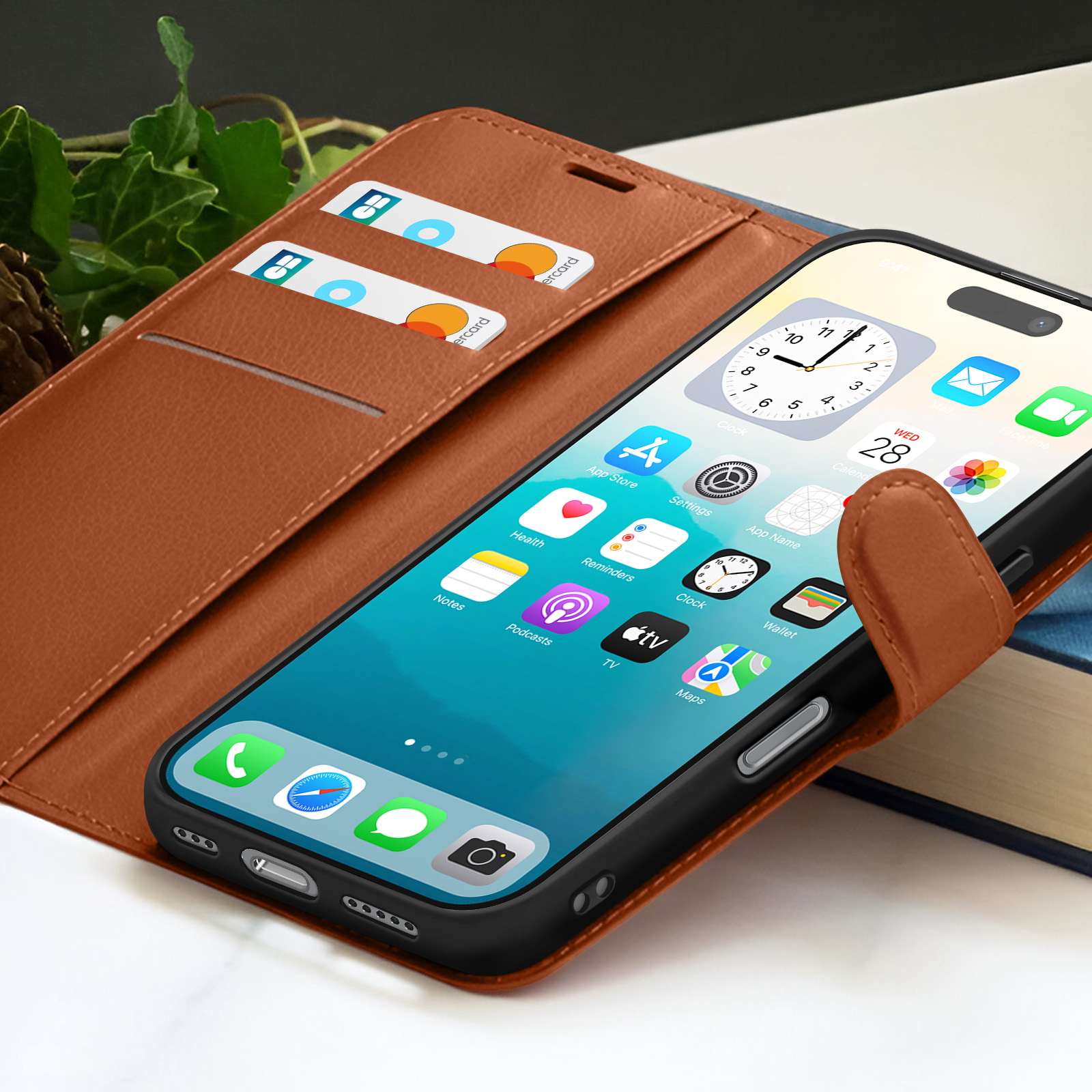 iPhone in een bruine leren hoes, met apps. Kaarten in de hoes. Groene bladeren zichtbaar op de achtergrond.
