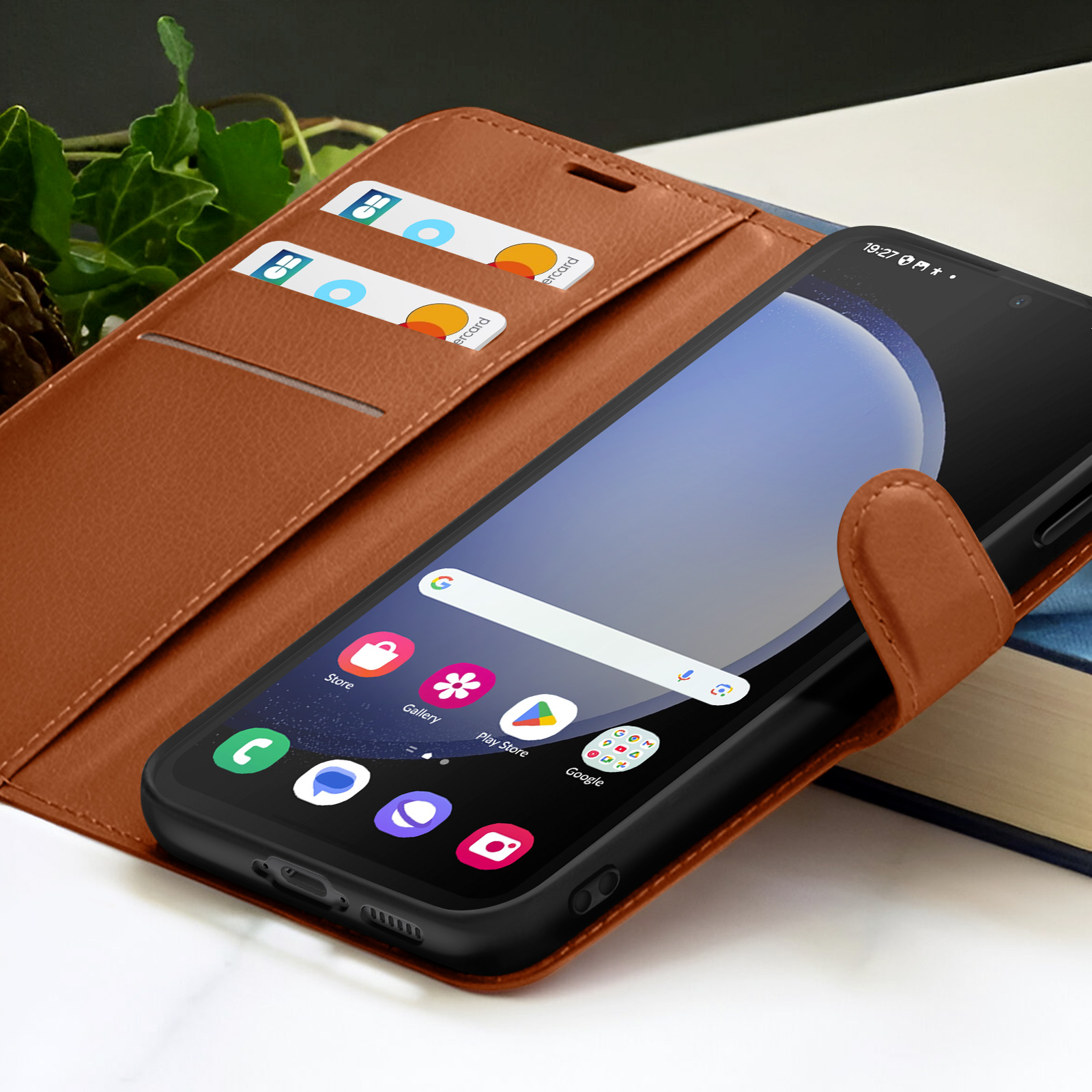 Een smartphone in een bruine leren hoes. Creditcards zitten in de hoes. Het scherm toont apps, tijd en een zoekbalk.