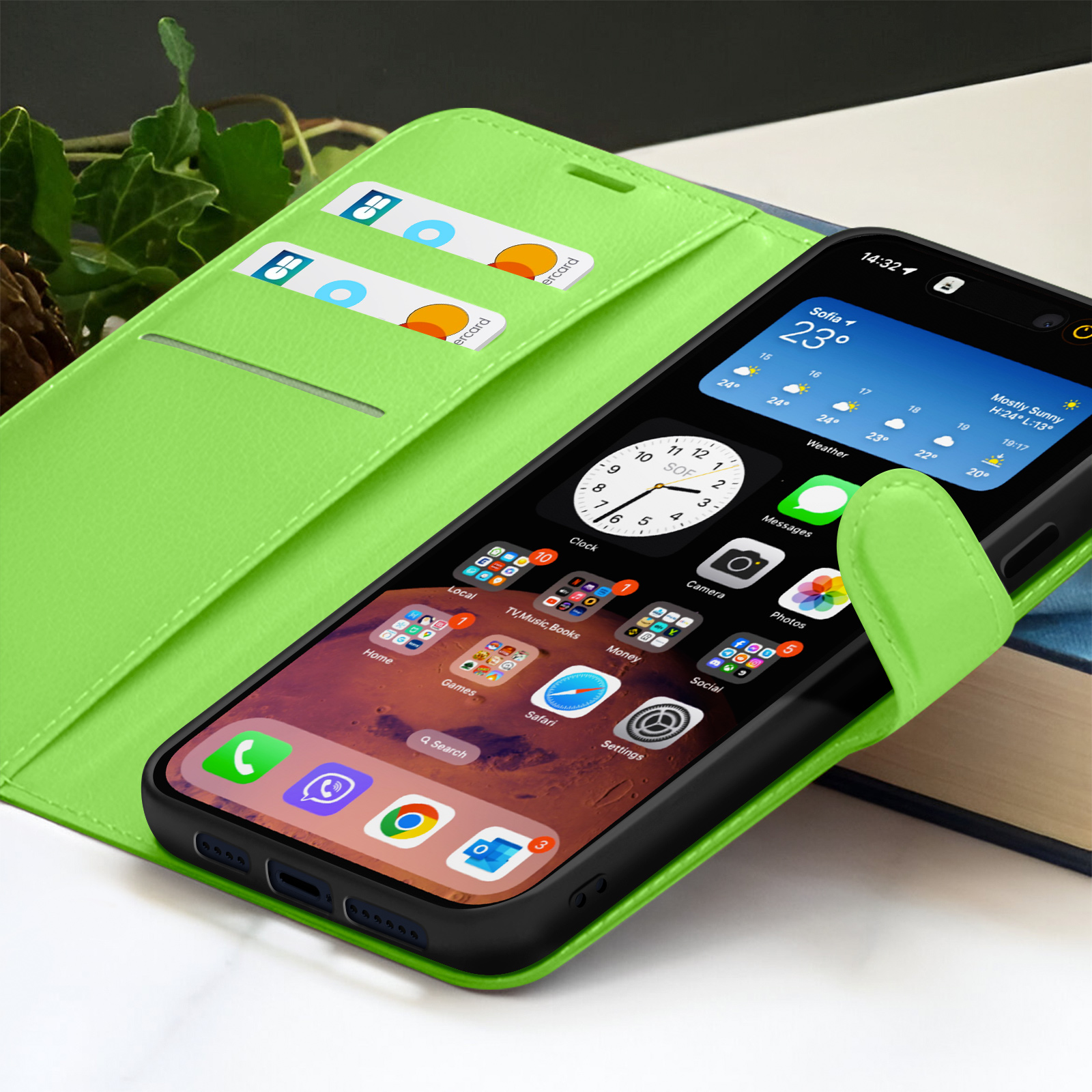 Een groene telefoonhoes met een telefoon waarop app-pictogrammen worden weergegeven. Er zitten creditcards in de hoes. Een boek staat op de achtergrond.