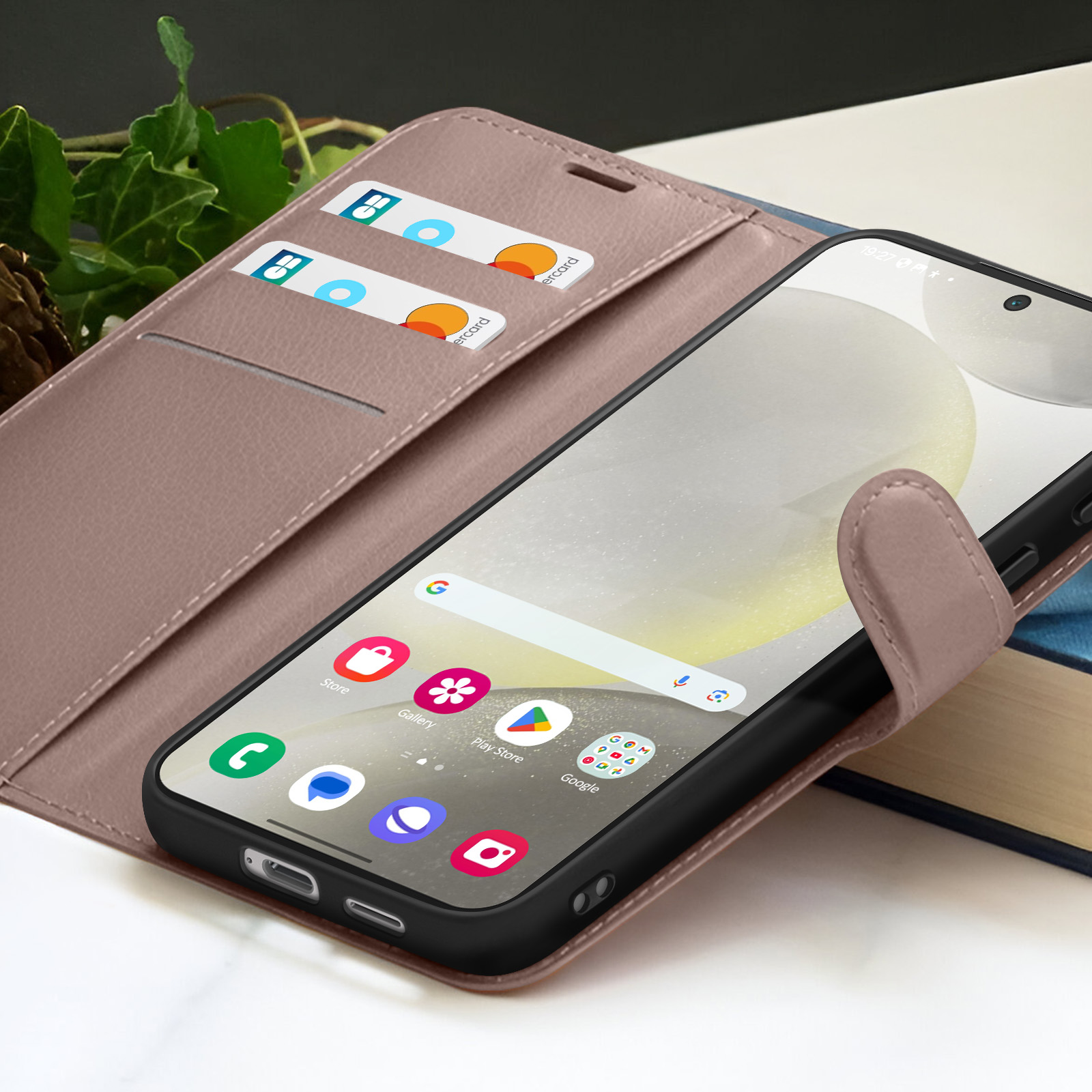 Een telefoon met een hoesje, met apps en twee kaarten in de cover. De achtergrond is een boek en wat bladeren.