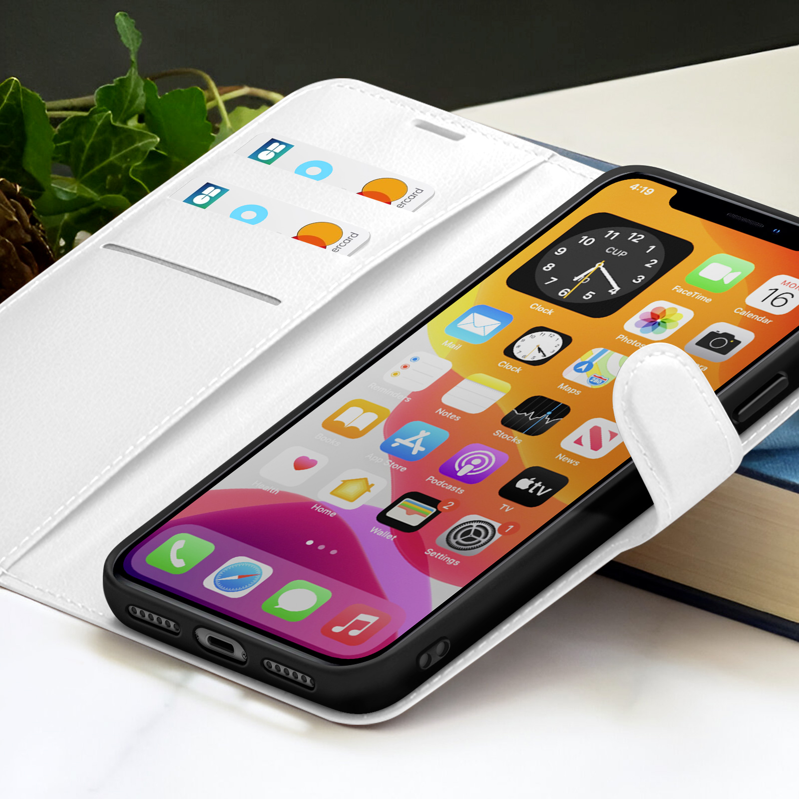 Ein Smartphone in einer weißen Hülle zeigt Apps. Das Telefon liegt auf einem Buch, Kreditkarten sind sichtbar.
