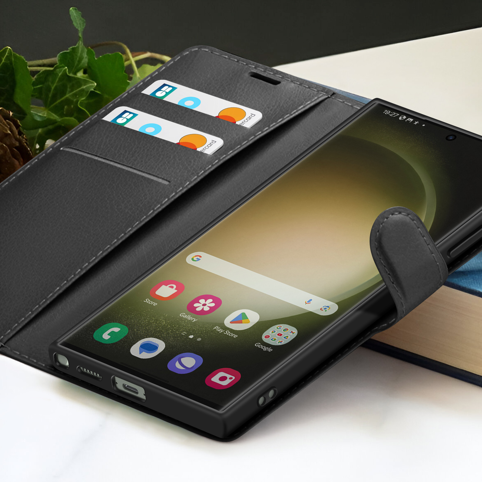 Een zwarte smartphone in een zwarte portemonnee. De telefoon toont het startscherm met apps. Creditcards in de portemonnee.