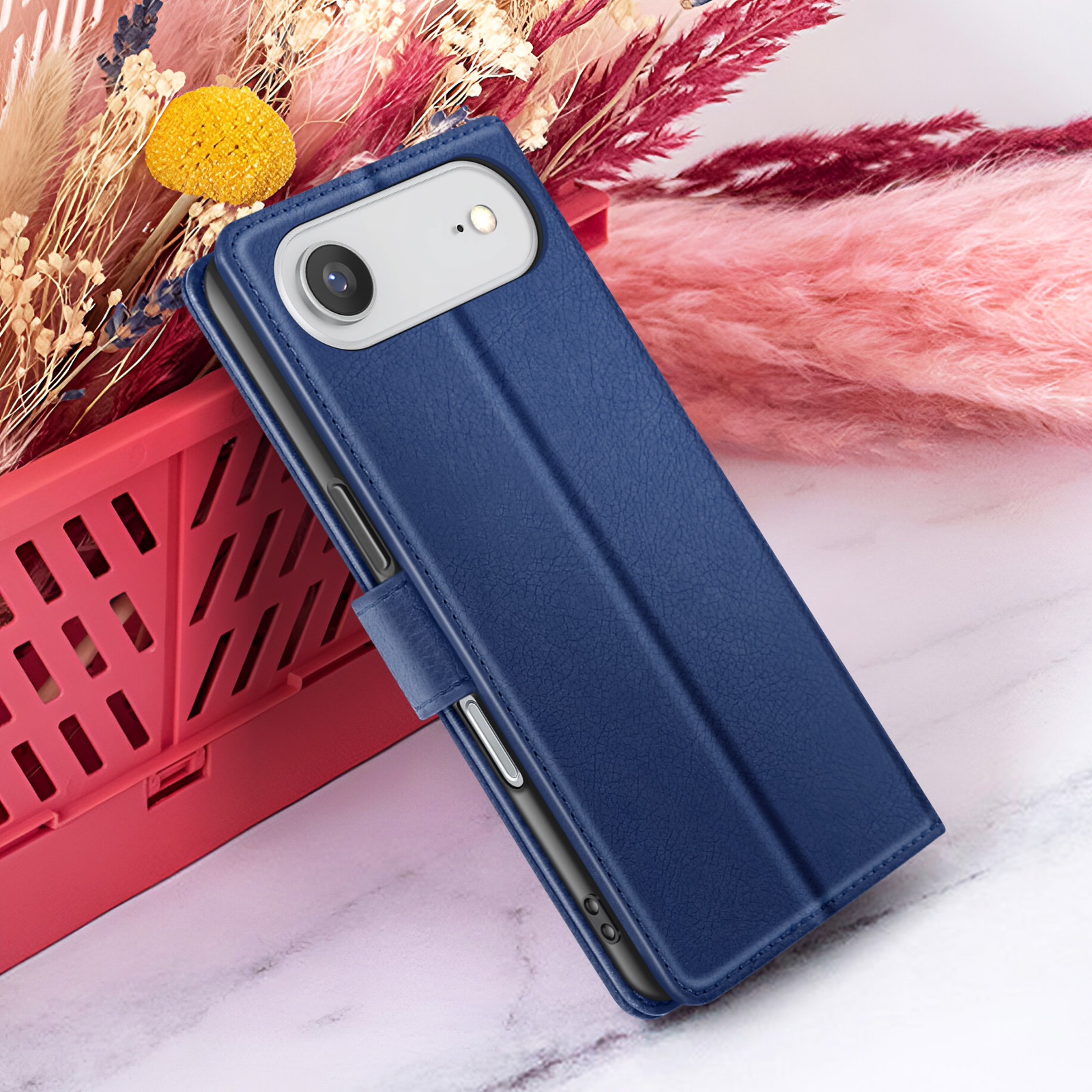 Una custodia blu per telefono è vicino a fiori in un cesto rosso. La custodia ha una fotocamera e una chiusura.