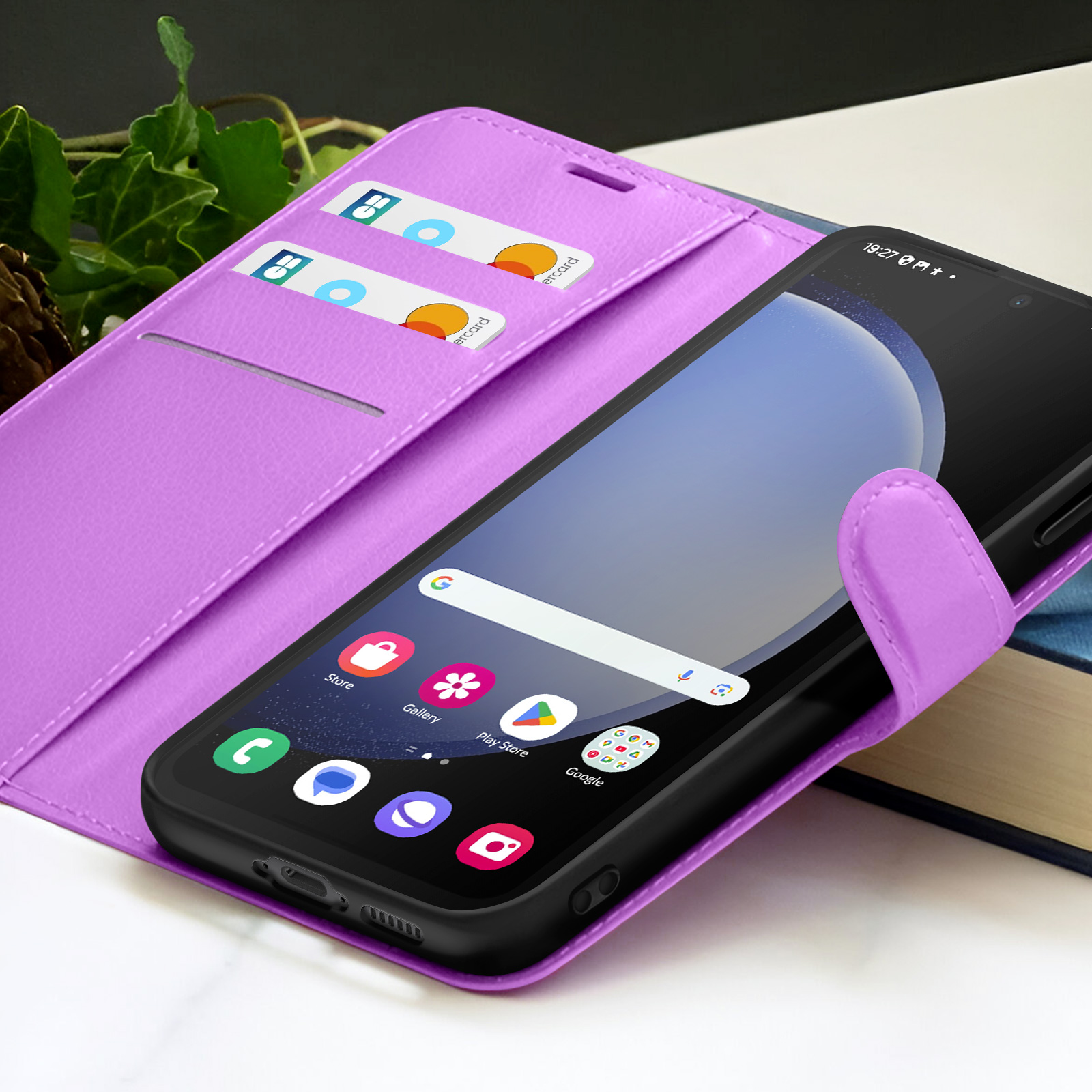 Een smartphone in een paarse case met creditcards. Het scherm toont app-iconen. Achtergrond: boek en groen.