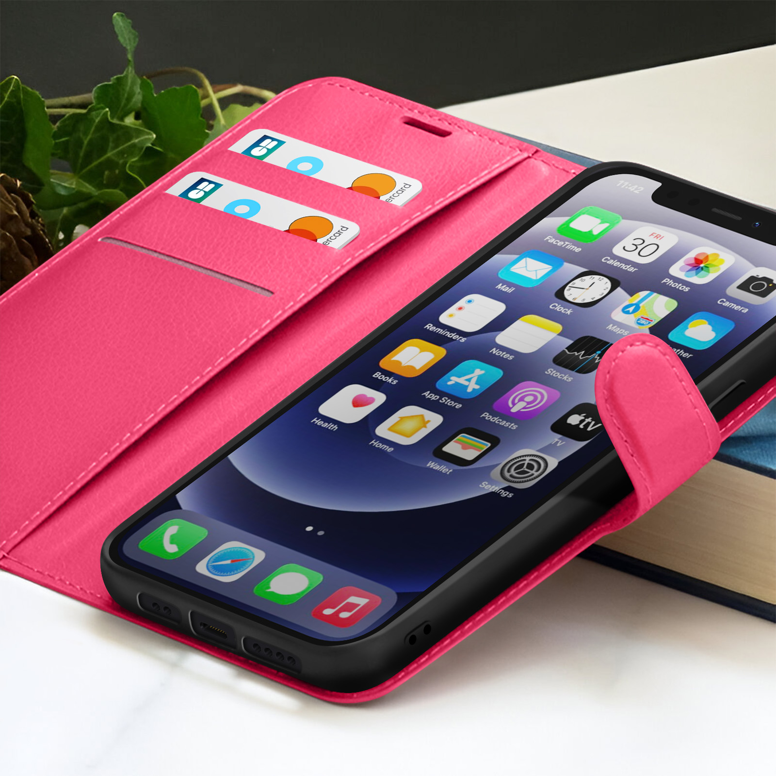 Custodia per telefono rosa con telefono che mostra le app. Carte di credito in uno slot. Fogliame verde sullo sfondo.
