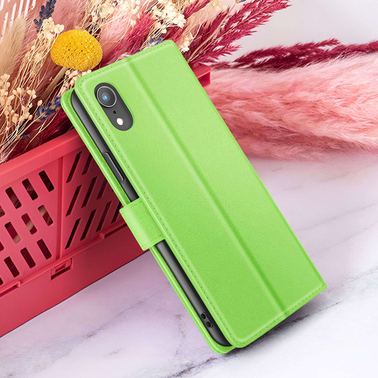 Coque de téléphone verte avec un téléphone à l'intérieur, sur fond de fleurs et de panier rouge.