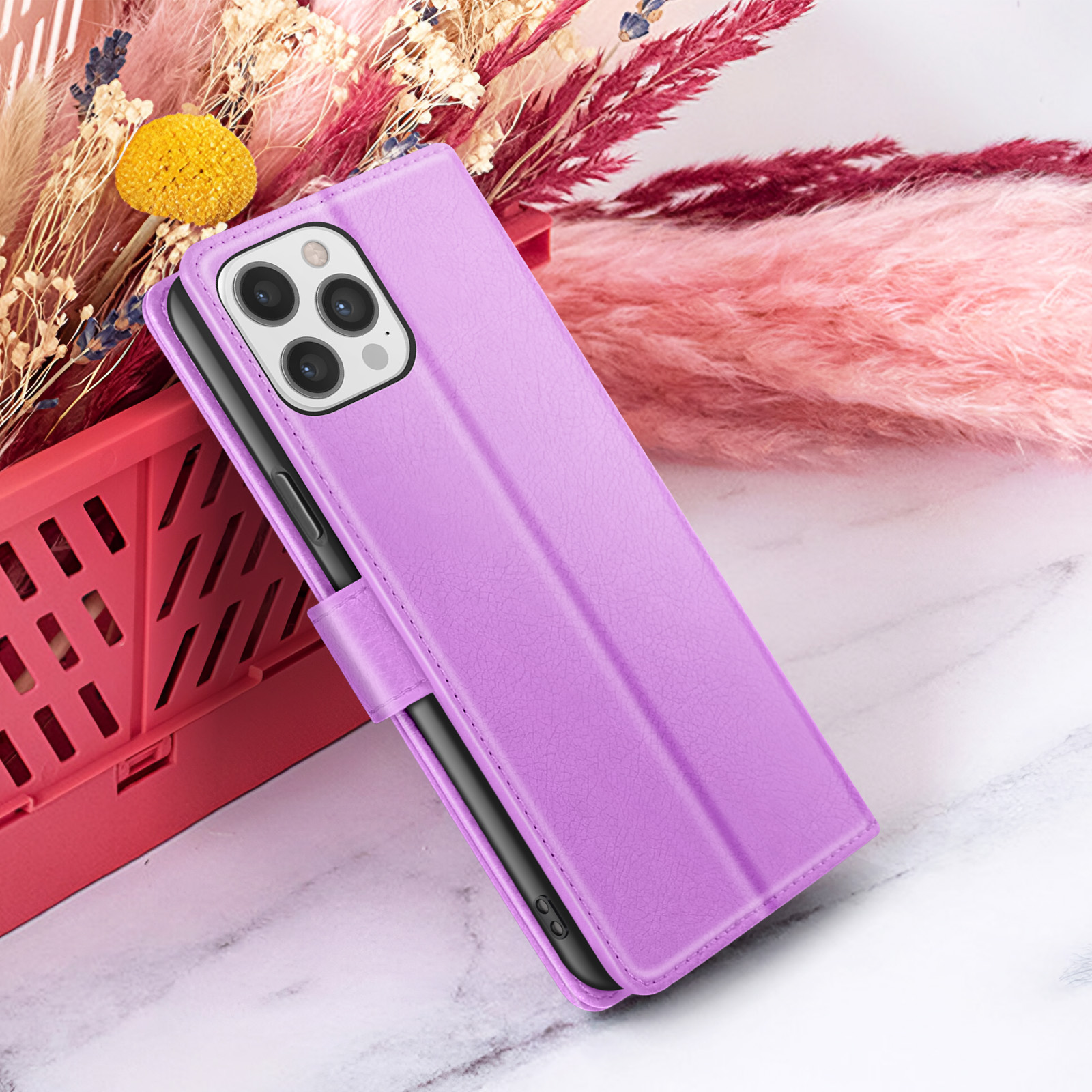 Een paarse telefoonhoes is open, met een telefoon erin. De achtergrond bevat bloemen en een marmeren oppervlak.