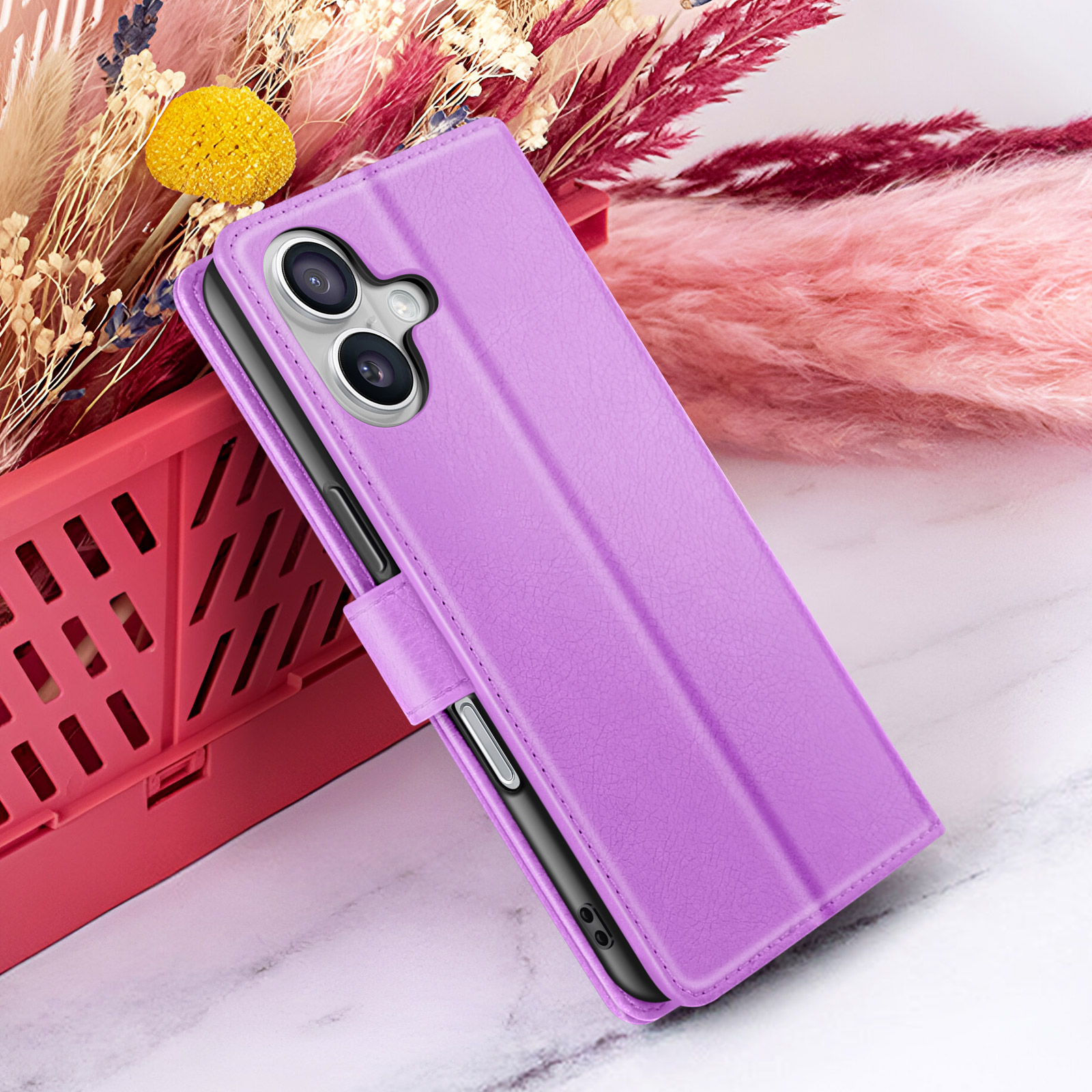 Una custodia viola con telefono, su marmo. Fiori decorativi sullo sfondo.