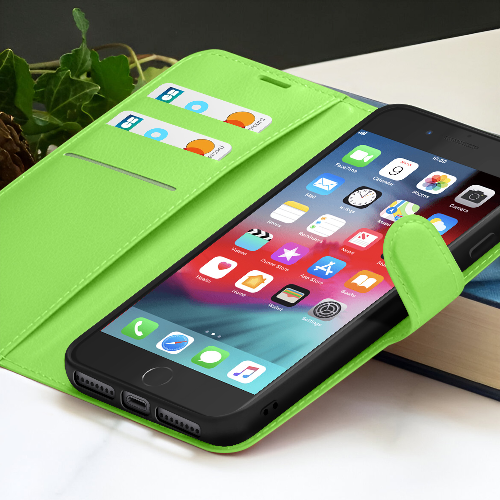 Een iPhone in een groene hoes, met app-iconen. Creditcards in de sleuven. Achtergrond: boek en bladeren.