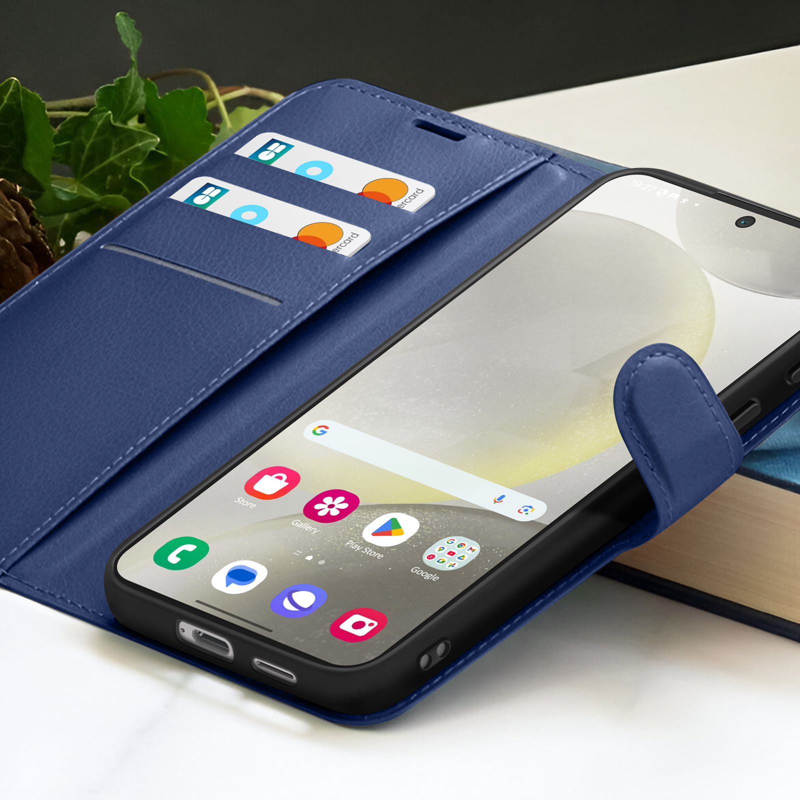 Een blauwe telefoonhoes met smartphone en app-pictogrammen. Twee creditcards in de hoes. Een boek op de achtergrond.