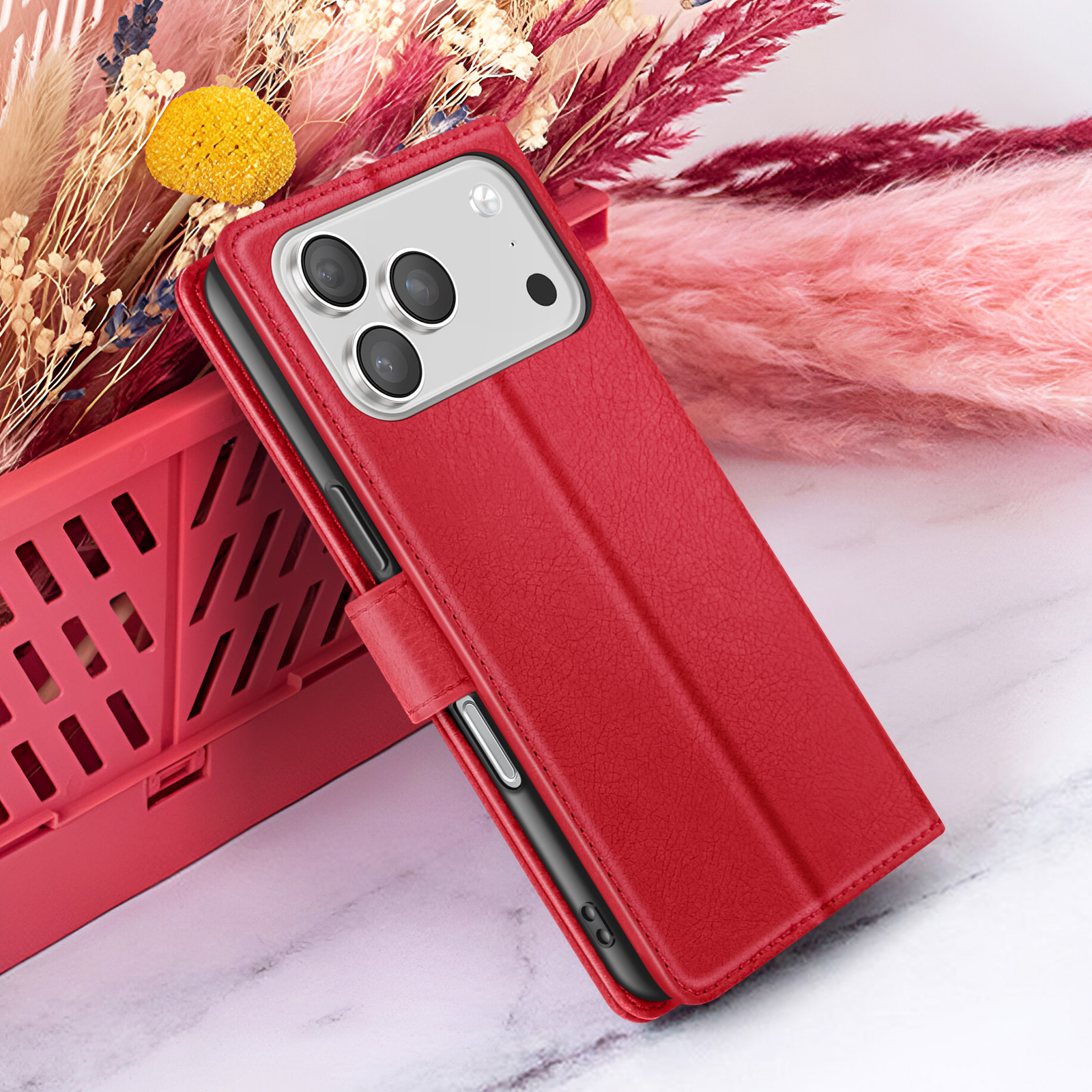 Rode telefoonhoes met camera, op een rode krat, met gedroogde bloemen op de achtergrond.