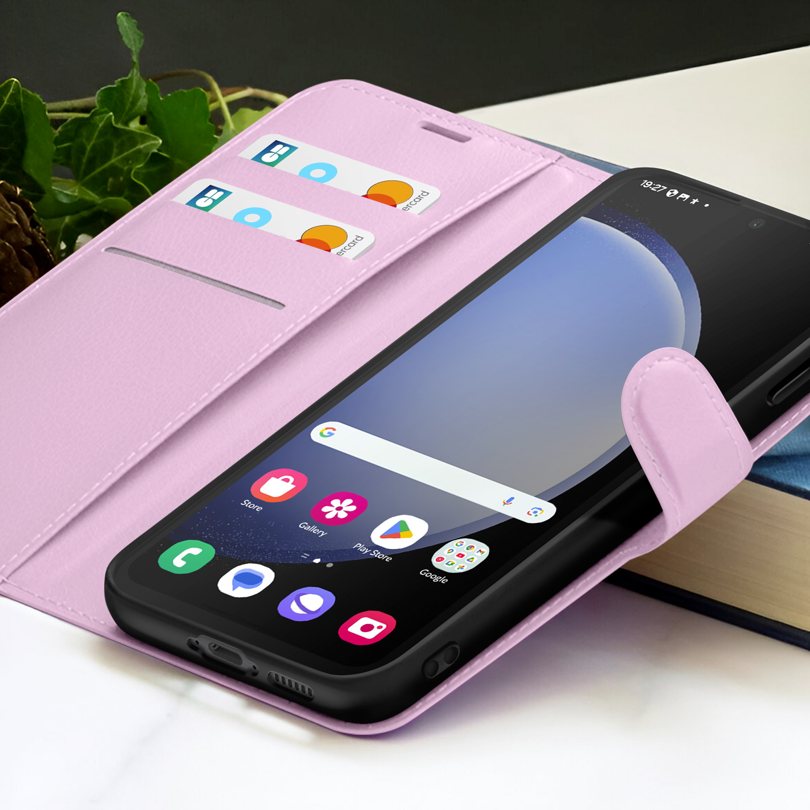 Een telefoon met een roze hoesje is open. De telefoon toont apps. Er zitten twee kaarten in de hoes.