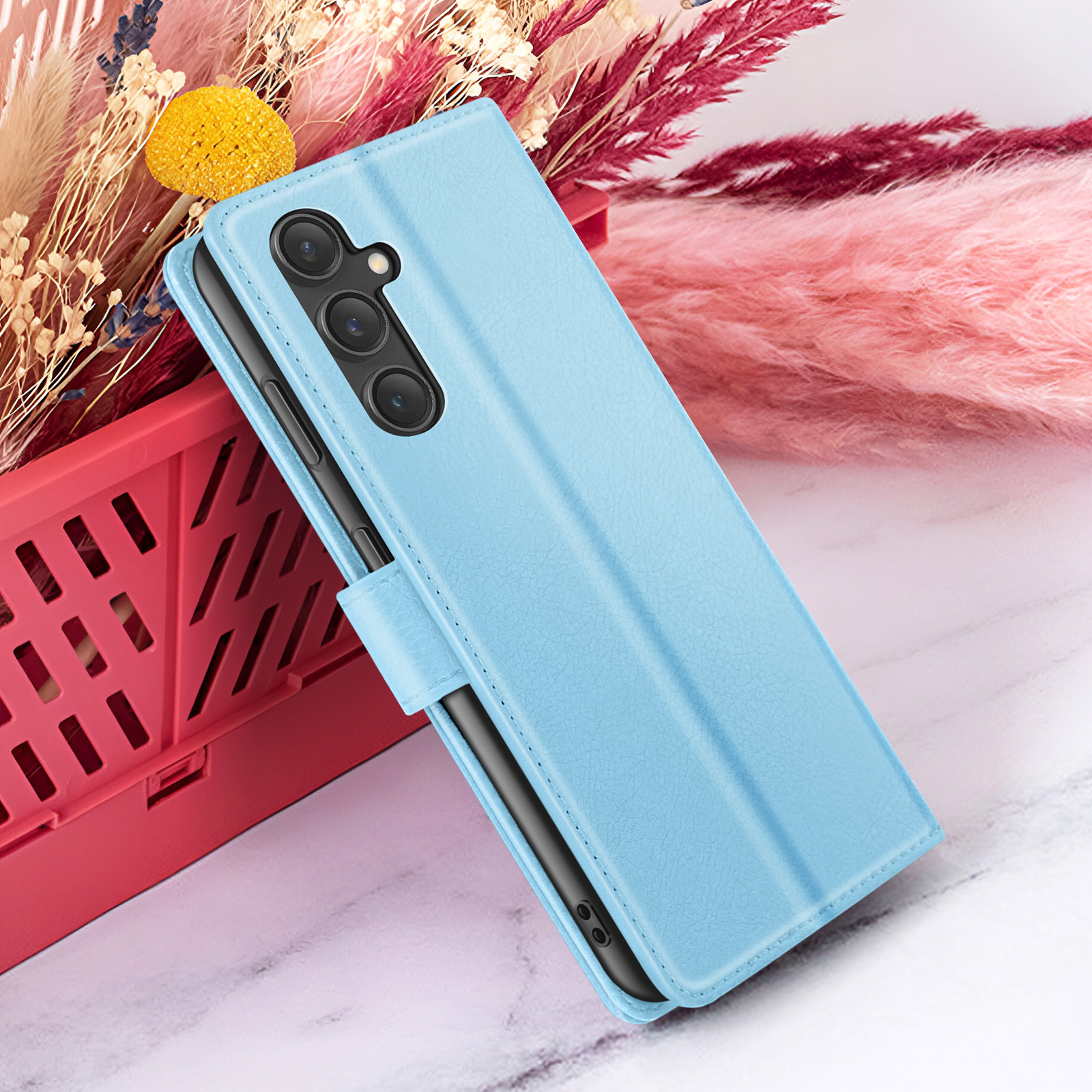 Een blauwe telefoonhoes met een telefoon erin, met een bloemenachtergrond en een rode mand.