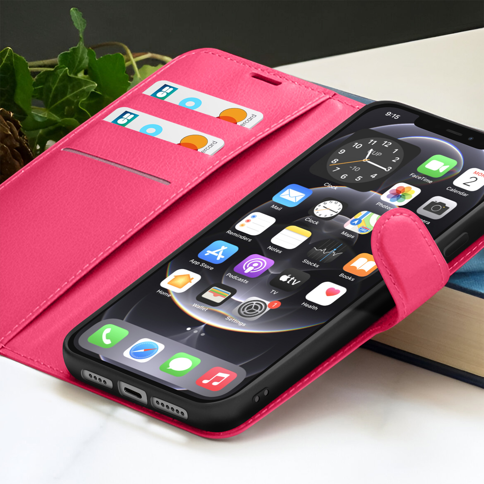 Custodia rosa con telefono nero che mostra le app. Carte di credito nella custodia e un libro sullo sfondo.