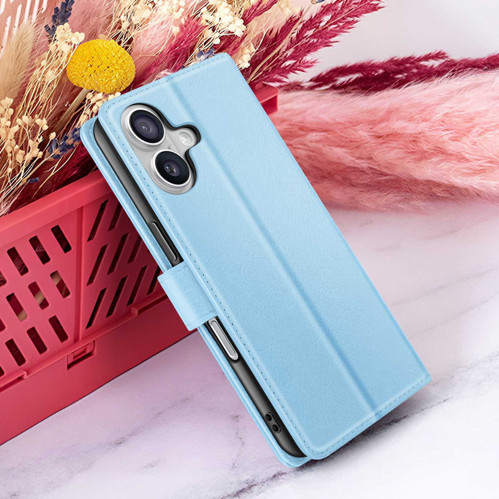 Una custodia per telefono azzurra è appoggiata a un contenitore rosso, con fiori sullo sfondo. La custodia ha una fotocamera.