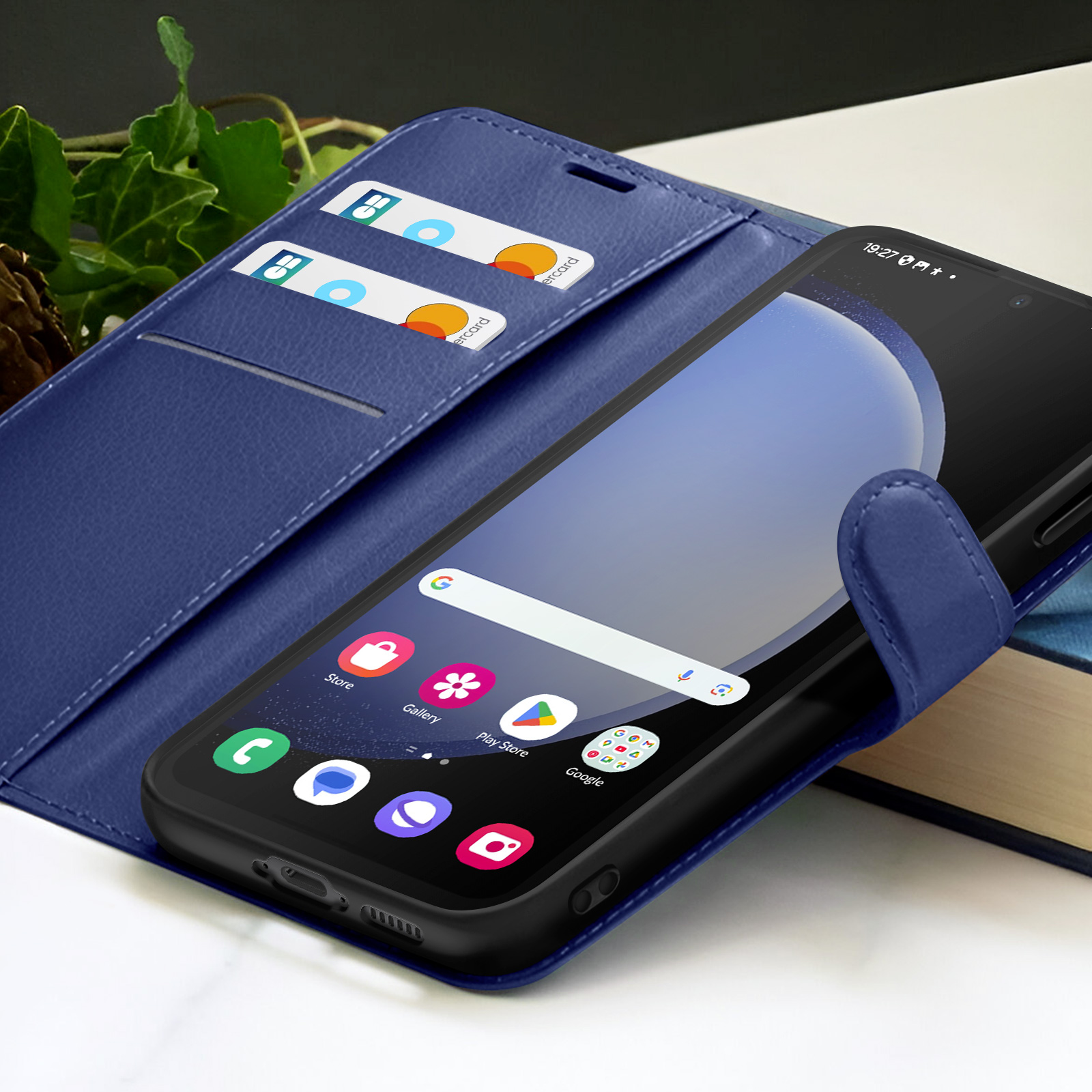 Un smartphone dans un étui bleu est ouvert, affichant l'écran d'accueil. Deux cartes de crédit sont dans une fente.