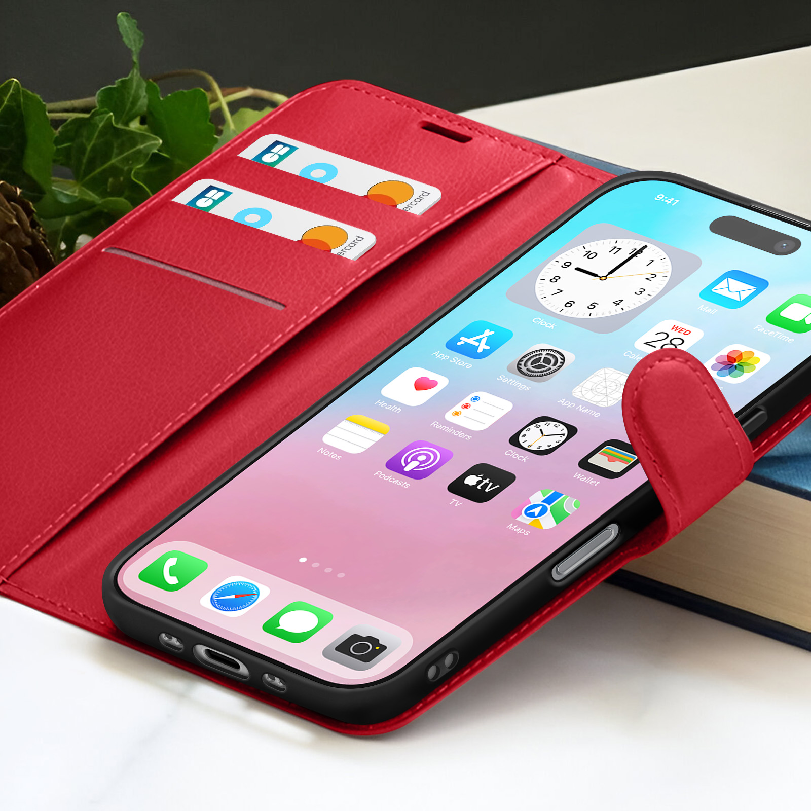 Rode telefoonhoes met een telefoon met app-iconen. Creditcards in de hoes. Klimop en een boek op de achtergrond.