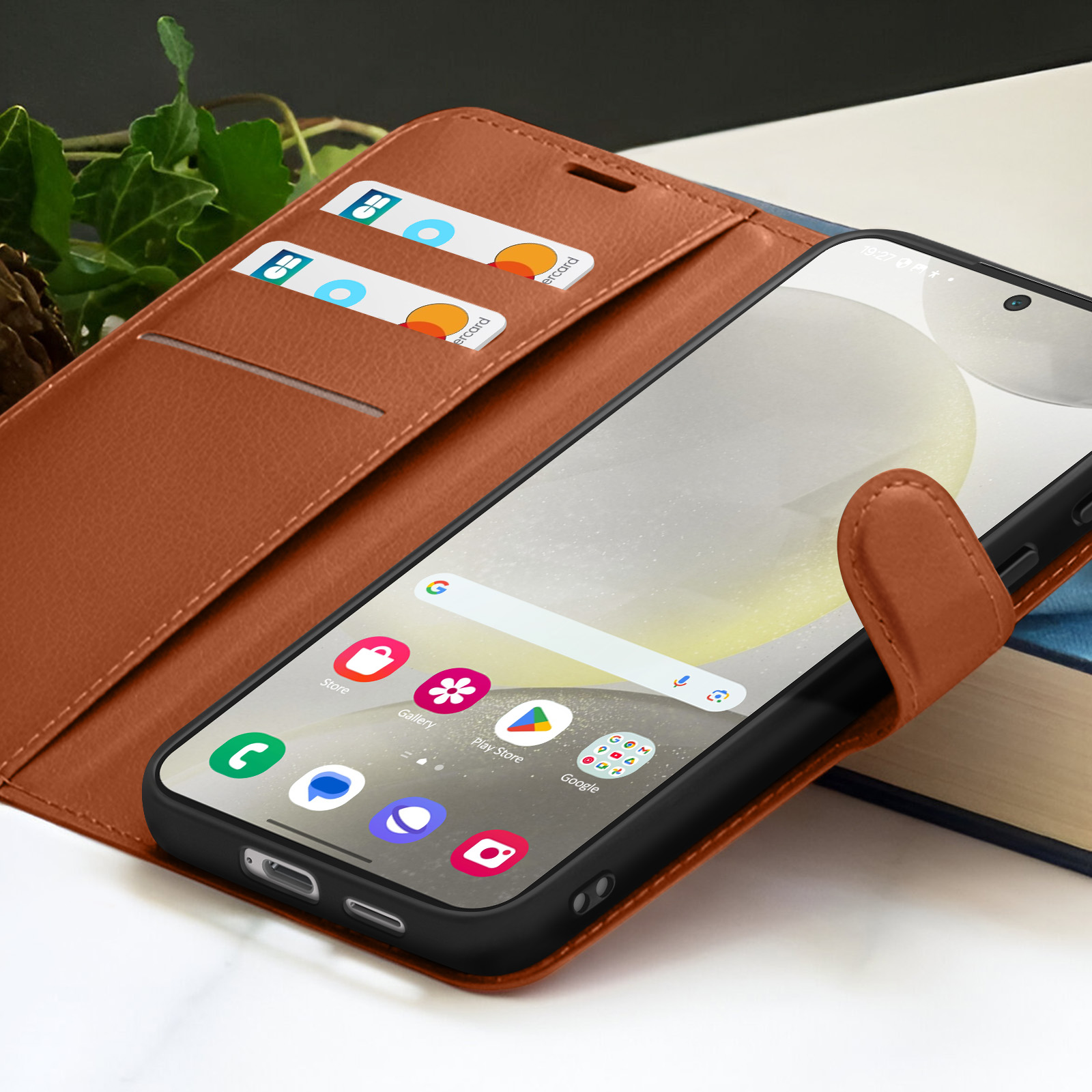 Un smartphone dans un étui en cuir marron, avec des cartes de crédit dans les fentes. L'écran affiche des icônes d'applications et une barre de recherche Google.