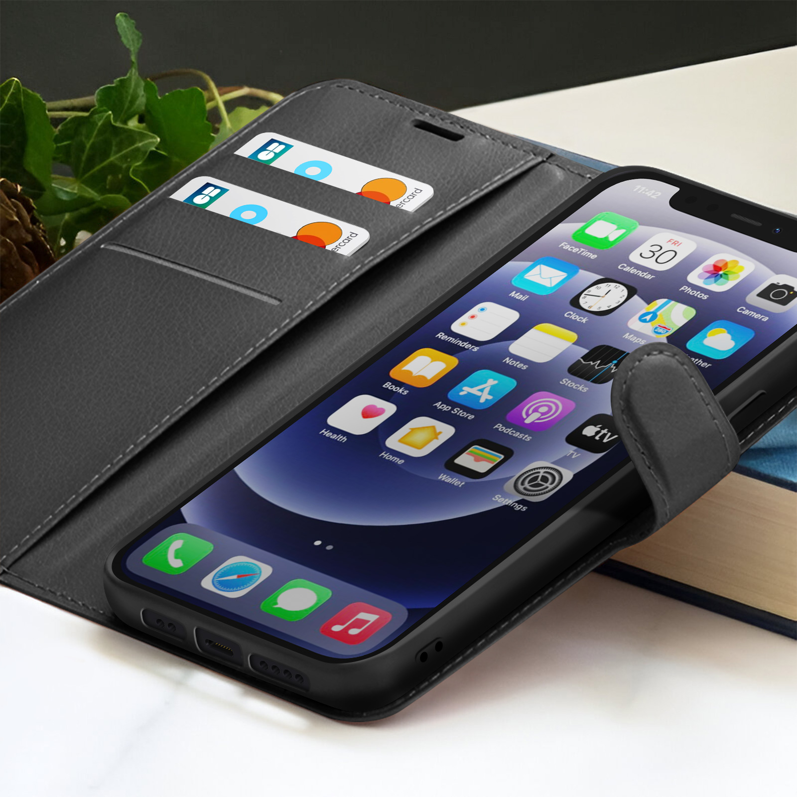 Uno smartphone in una custodia a libro mostra le icone delle app. Carte di credito nella custodia. Un libro e foglie sullo sfondo.