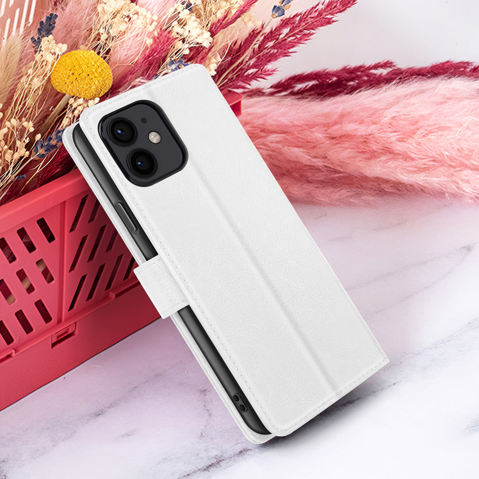 Custodia bianca per telefono con un telefono all'interno. Lo sfondo include fiori e una superficie rosa.