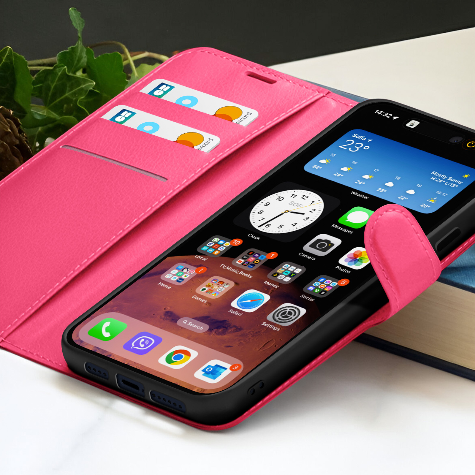 Telefoon in roze hoesje, met weer- en app-iconen. Twee kaarten zichtbaar in de hoes. Boeken op de achtergrond.