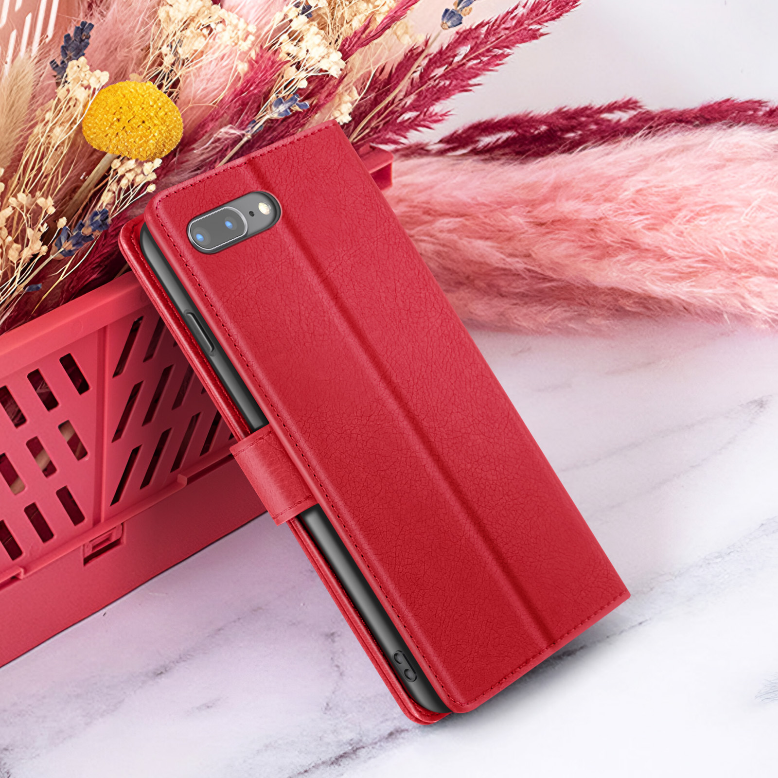 Étui de téléphone rouge avec un téléphone à l'intérieur, avec des fleurs en arrière-plan. L'étui est ouvert. Le fond est clair.