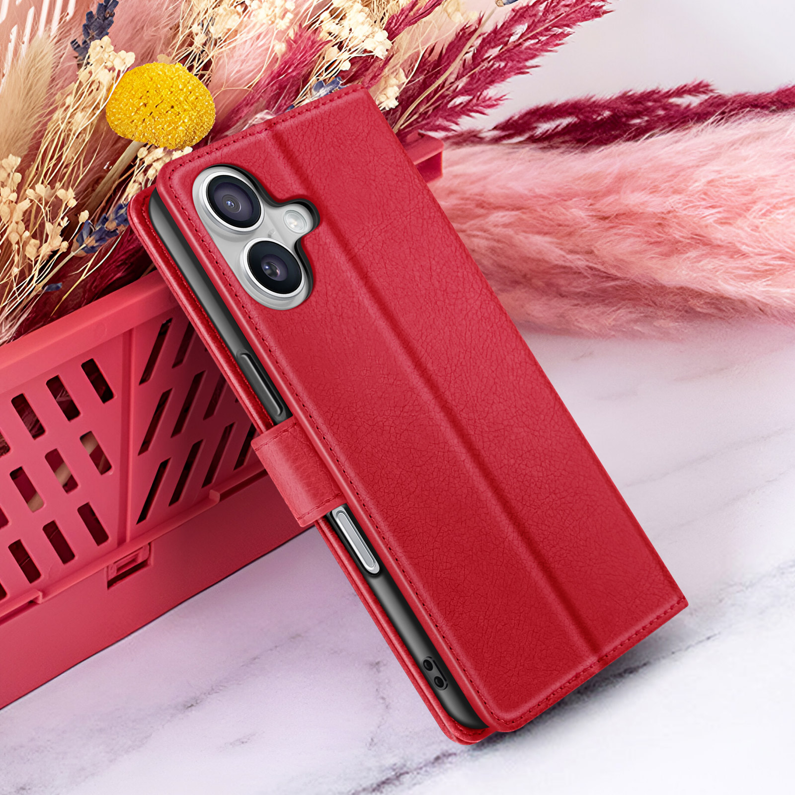 Rote Handyhülle mit Telefon auf Marmoroberfläche. Trockenblumen im Hintergrund, mit gelber Blüte.