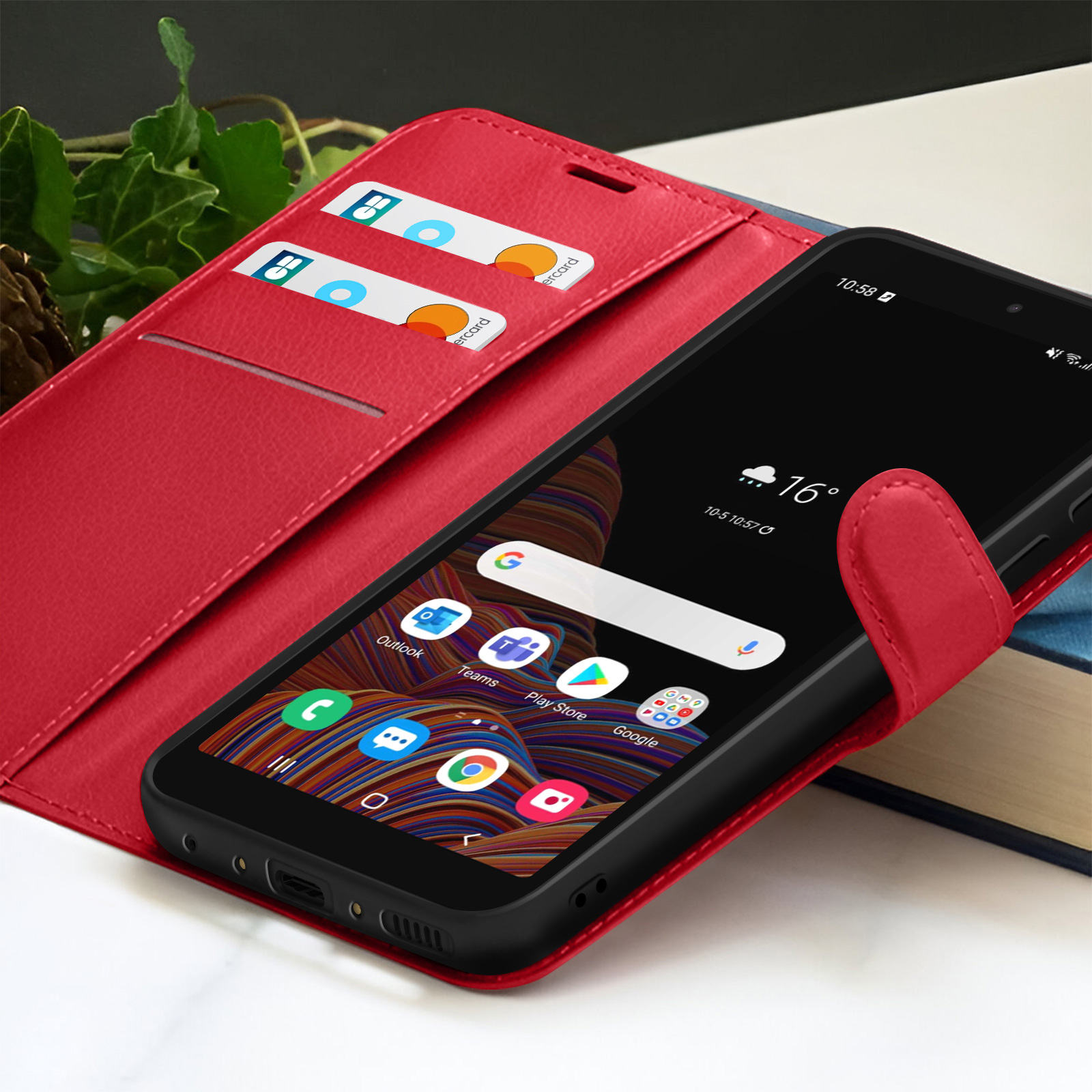 Rode telefoonhoes met een zwarte smartphone met apps en weer. Creditcards in de hoes. Boeken op de achtergrond.
