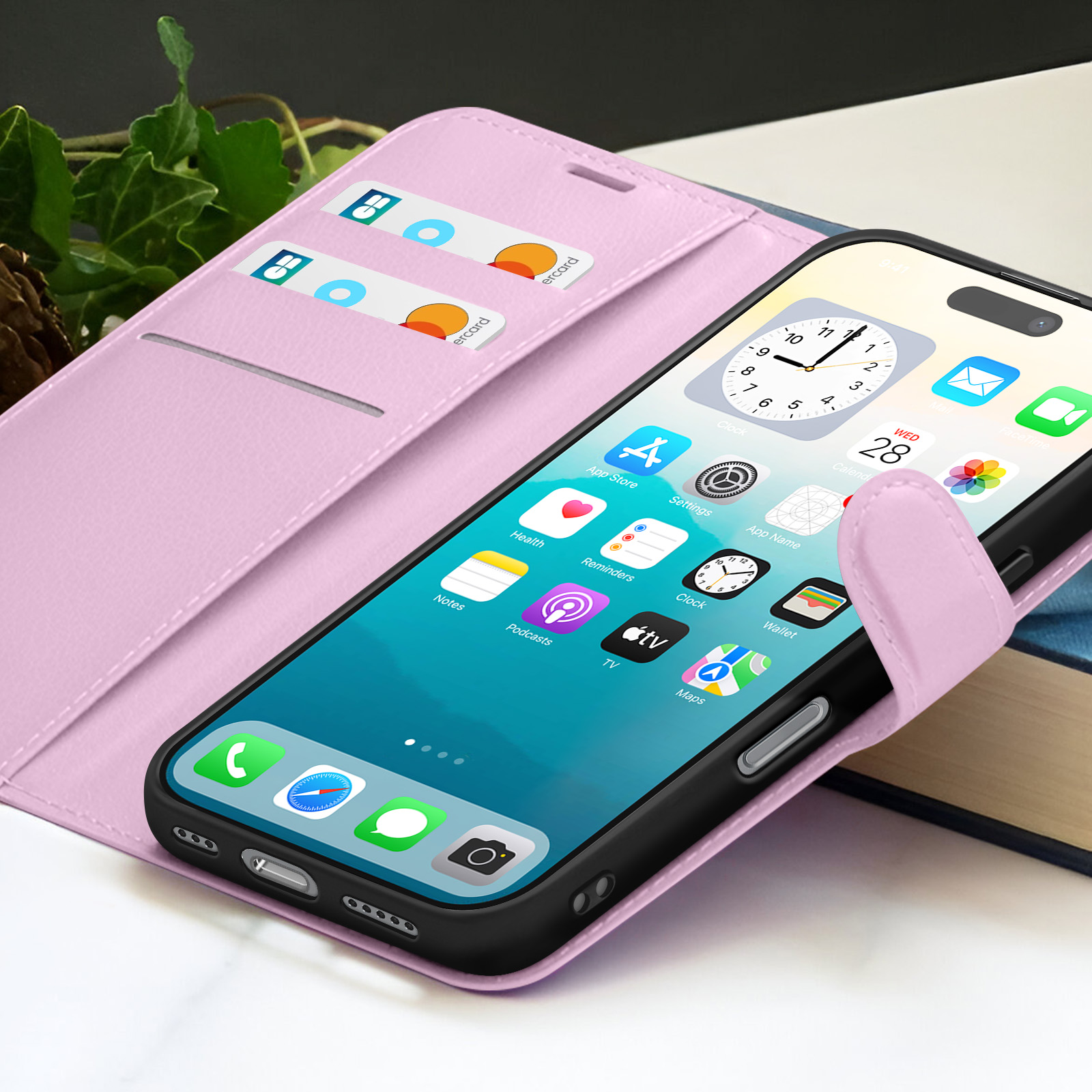 Een iPhone in een roze hoesje toont apps. Er zitten creditcards in het hoesje. Rechts is een boek.
