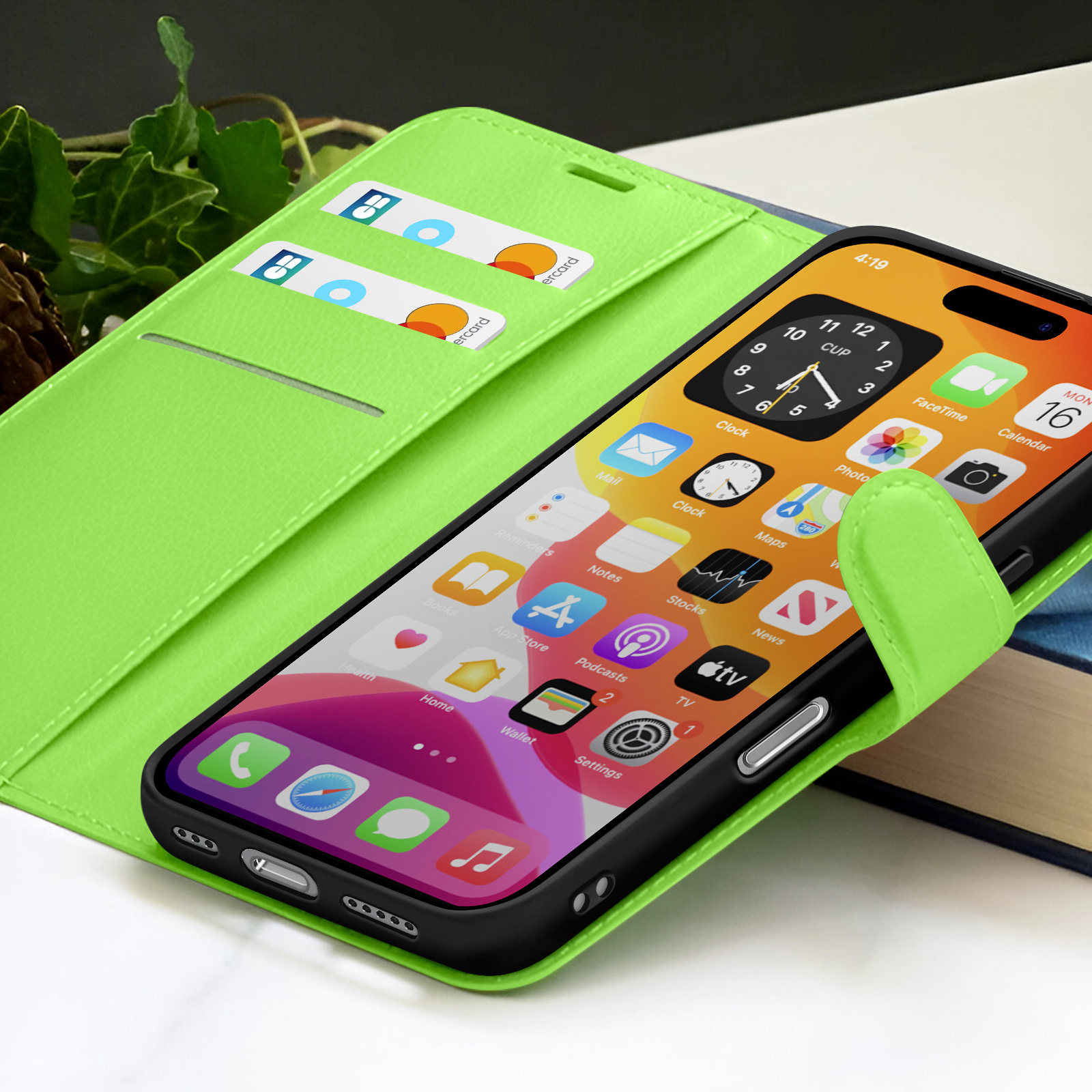 Un smartphone affiche des icônes et une horloge. Il est dans un étui vert avec des cartes de crédit. Un livre en arrière-plan.