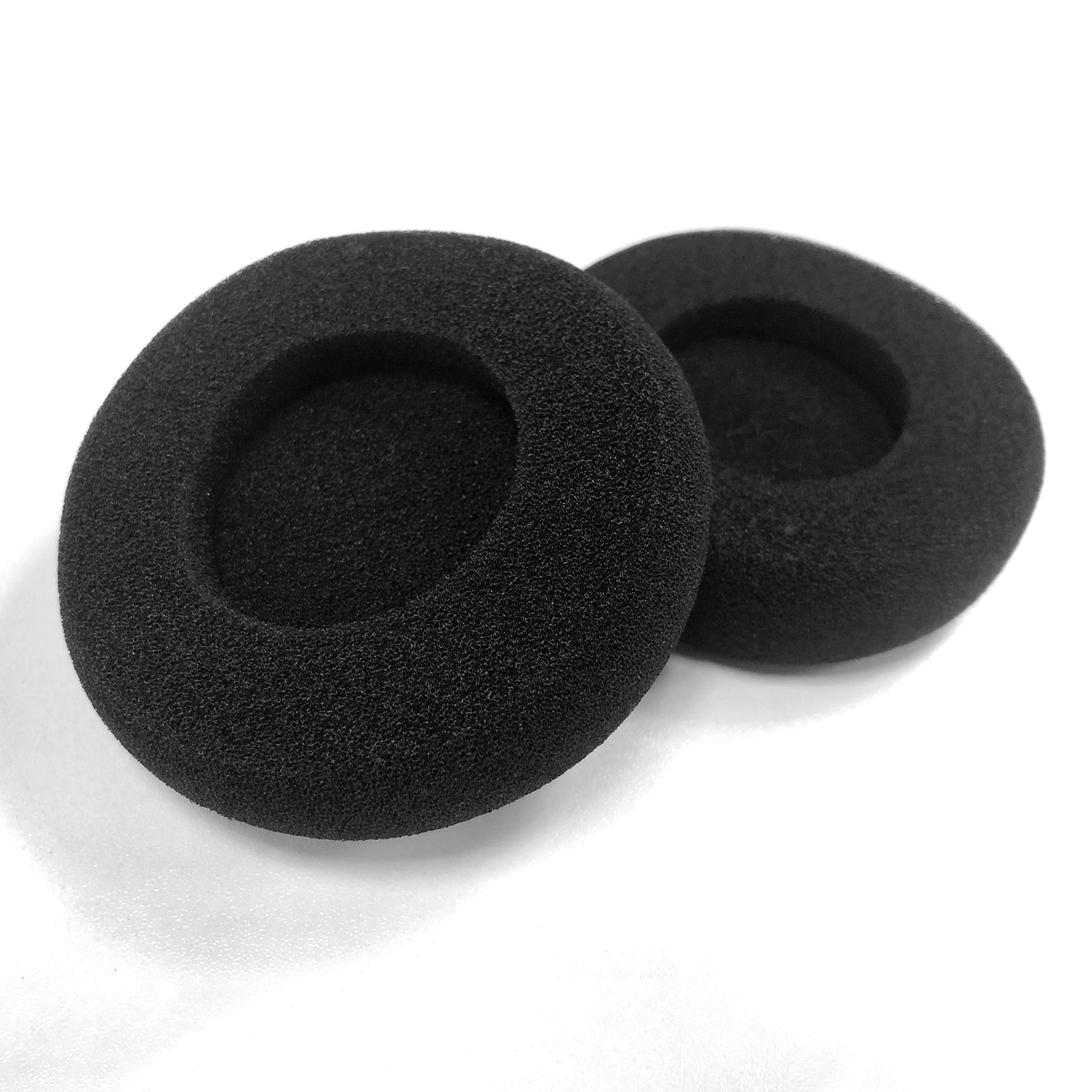 Zwei schwarze, runde Kopfhörer-Ohrpolster liegen auf einer weißen Oberfläche. Jedes Kissen ist ein Ring mit einem zentralen Loch.