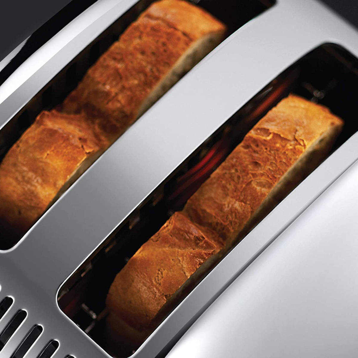Nahaufnahme eines Toasters mit zwei Brotscheiben. Das Brot ist goldbraun. Der Toaster ist silberfarben.