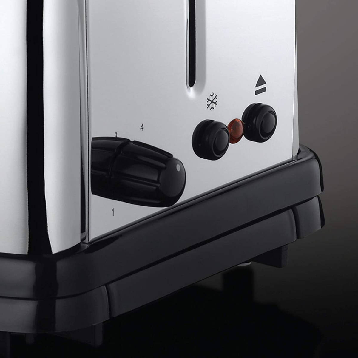 Nahaufnahme eines silbernen Toasters mit schwarzen Bedienelementen. Knöpfe, ein Schneeflockensymbol und ein Licht sind sichtbar. Zahlen zeigen den Röstgrad an.