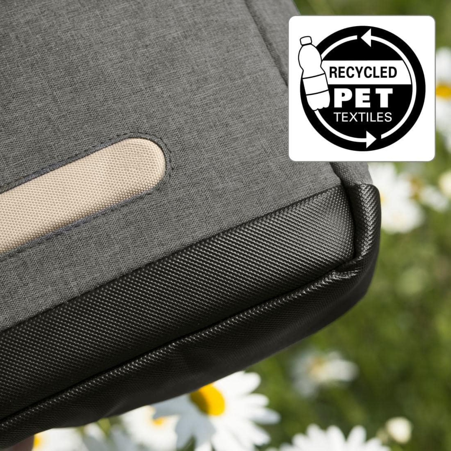 Szara torba z tkaniny z beżowym uchwytem. Widoczne logo tekstyliów z recyklingu PET. Białe kwiaty z żółtymi środkami w tle.