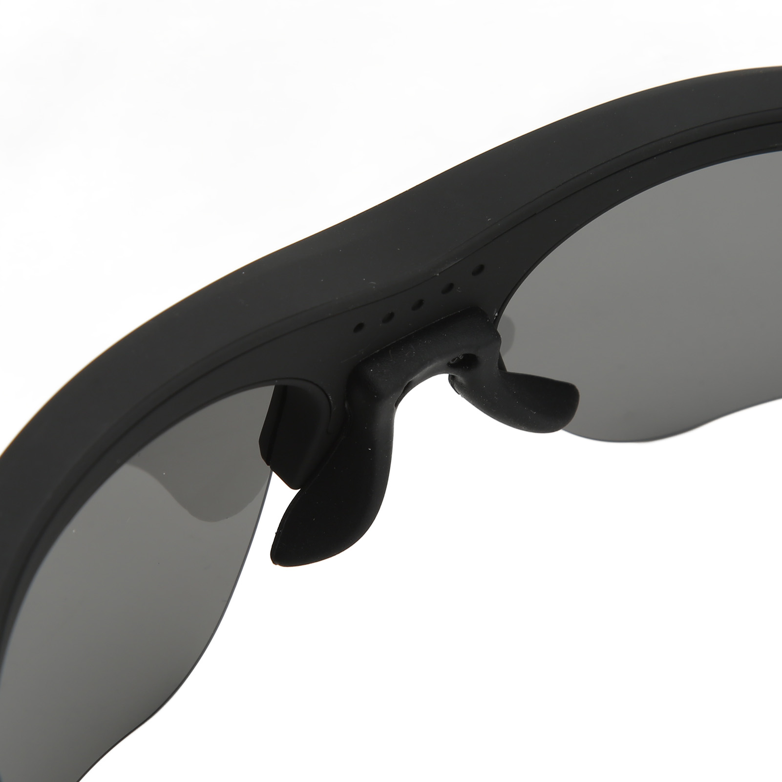Nahaufnahme einer schwarzen Sonnenbrille mit grauen Gläsern. Nasenpads und Rahmendetails sind vor weißem Hintergrund sichtbar.