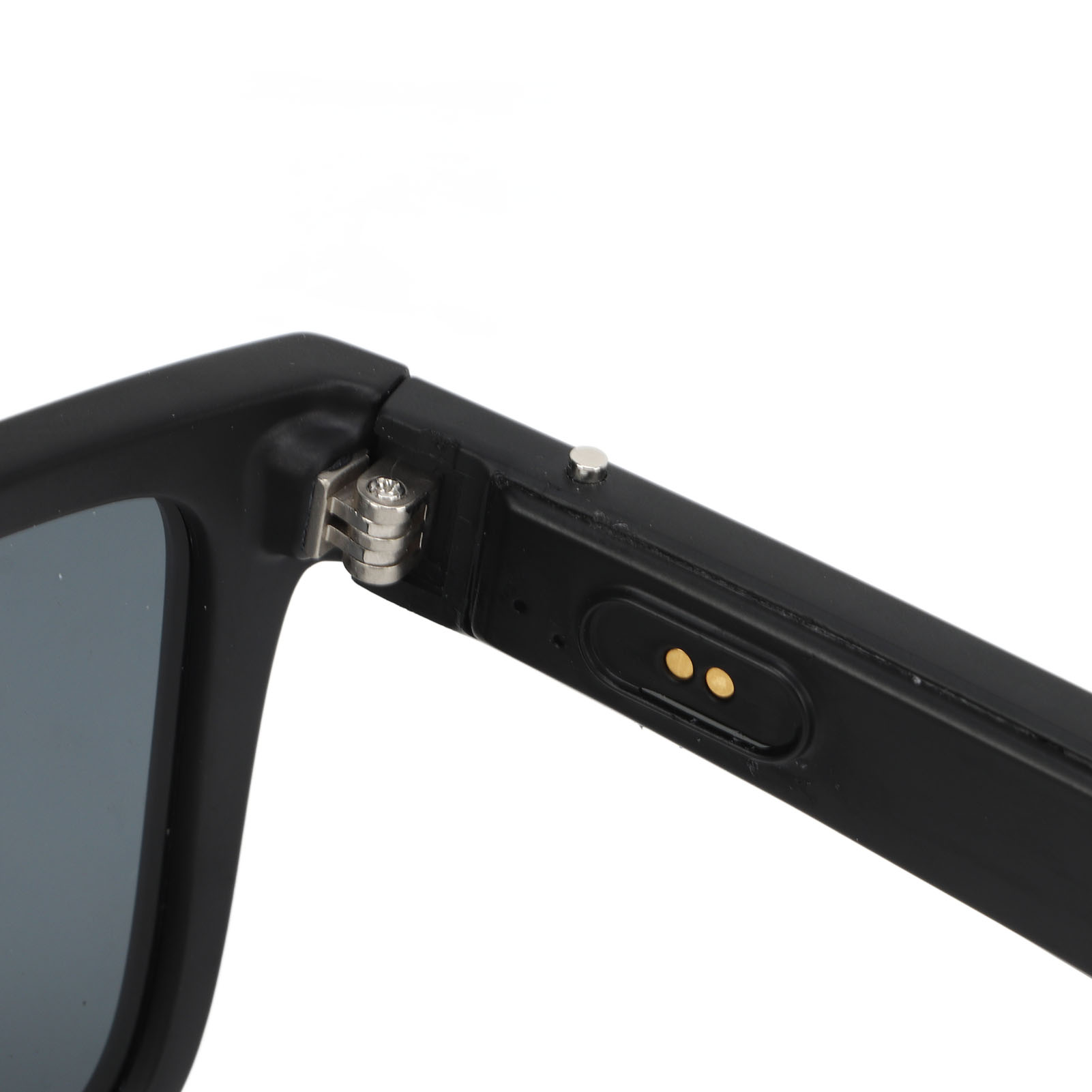 Nahaufnahme einer schwarzen Sonnenbrille. Das Scharnier ist sichtbar, zusammen mit einem Ladeanschluss und goldenen Punkten am Bügel.