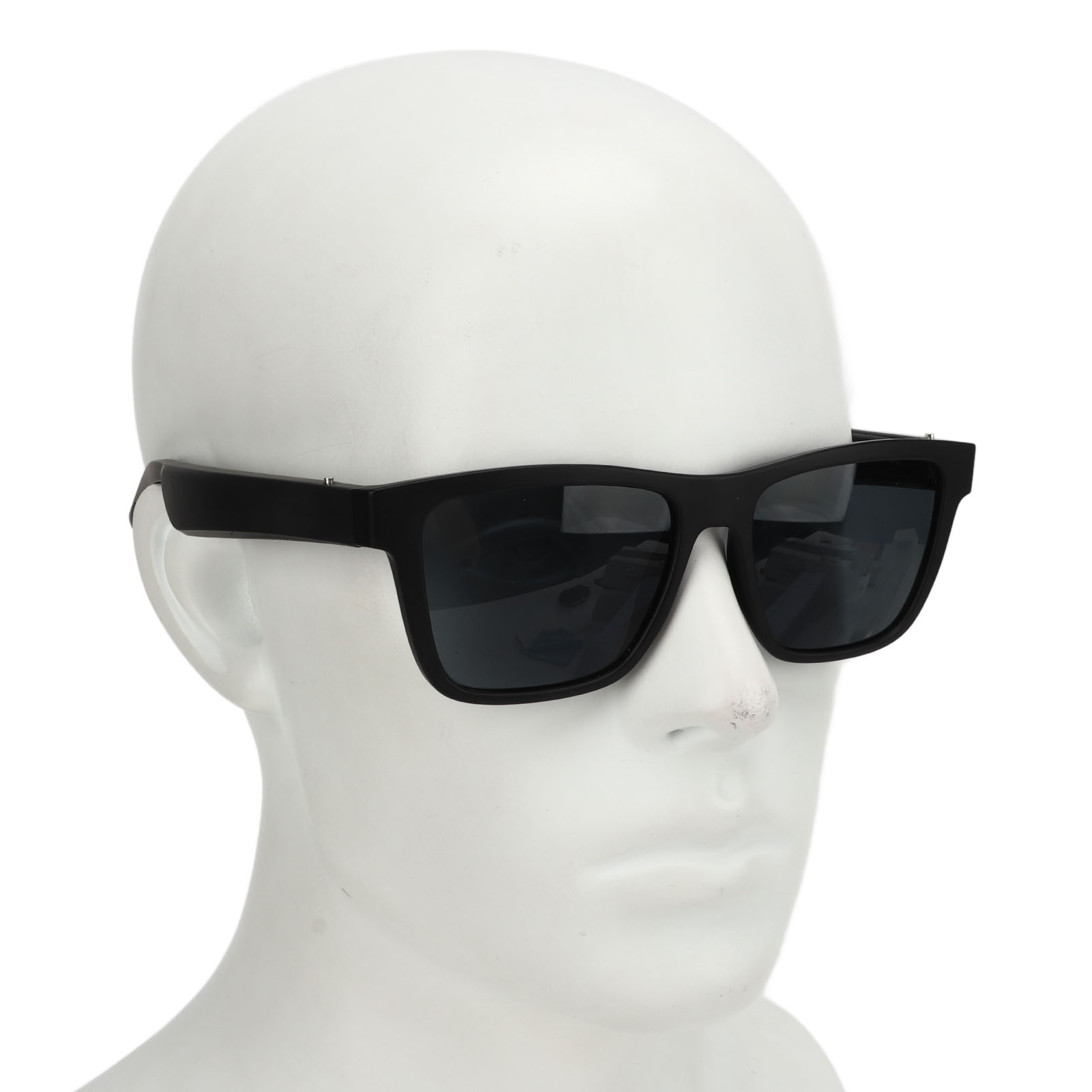 Ein weißer Schaufensterpuppenkopf mit schwarzer Sonnenbrille. Die Gläser sind dunkel und haben dicke Rahmen. Der Hintergrund ist weiß.