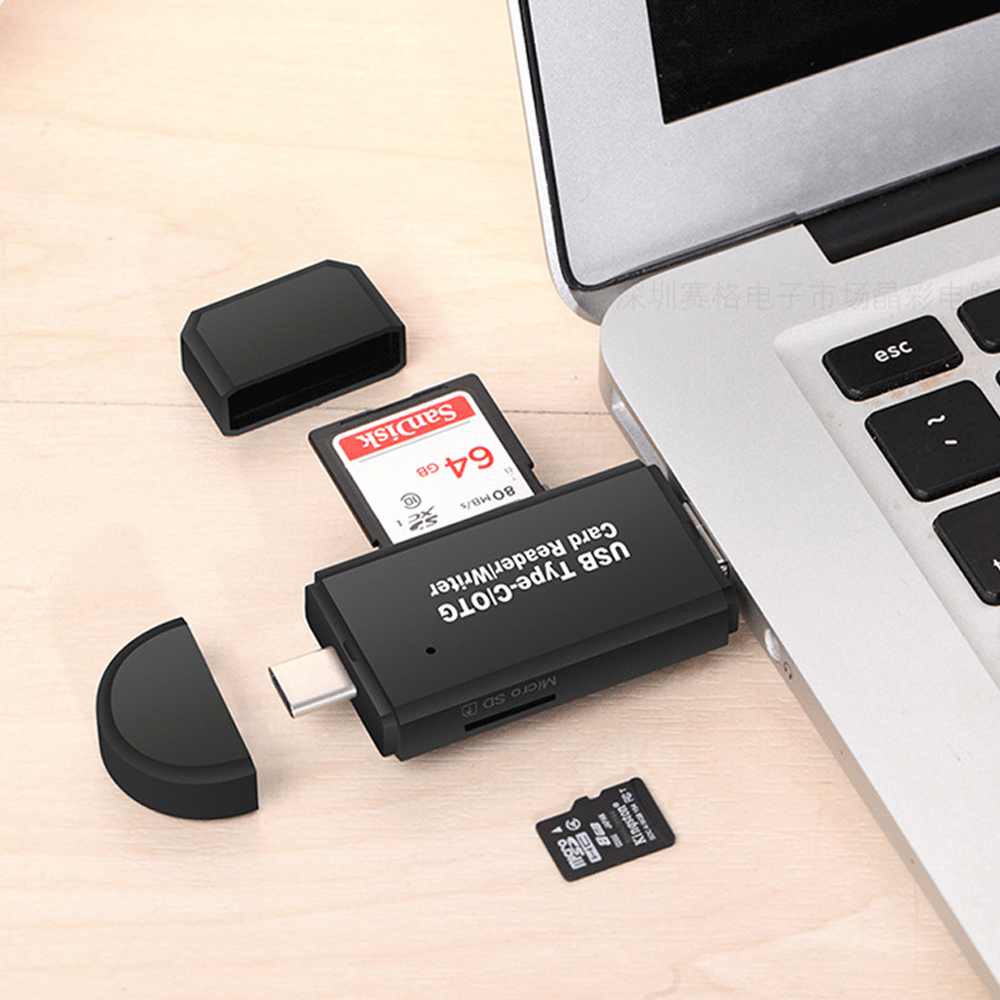 Ein schwarzer USB-Typ-C-Kartenleser mit einer Sandisk SD-Karte und einer Kingston Micro SD-Karte in der Nähe eines Laptops. Der Leser befindet sich auf einer Holzoberfläche.