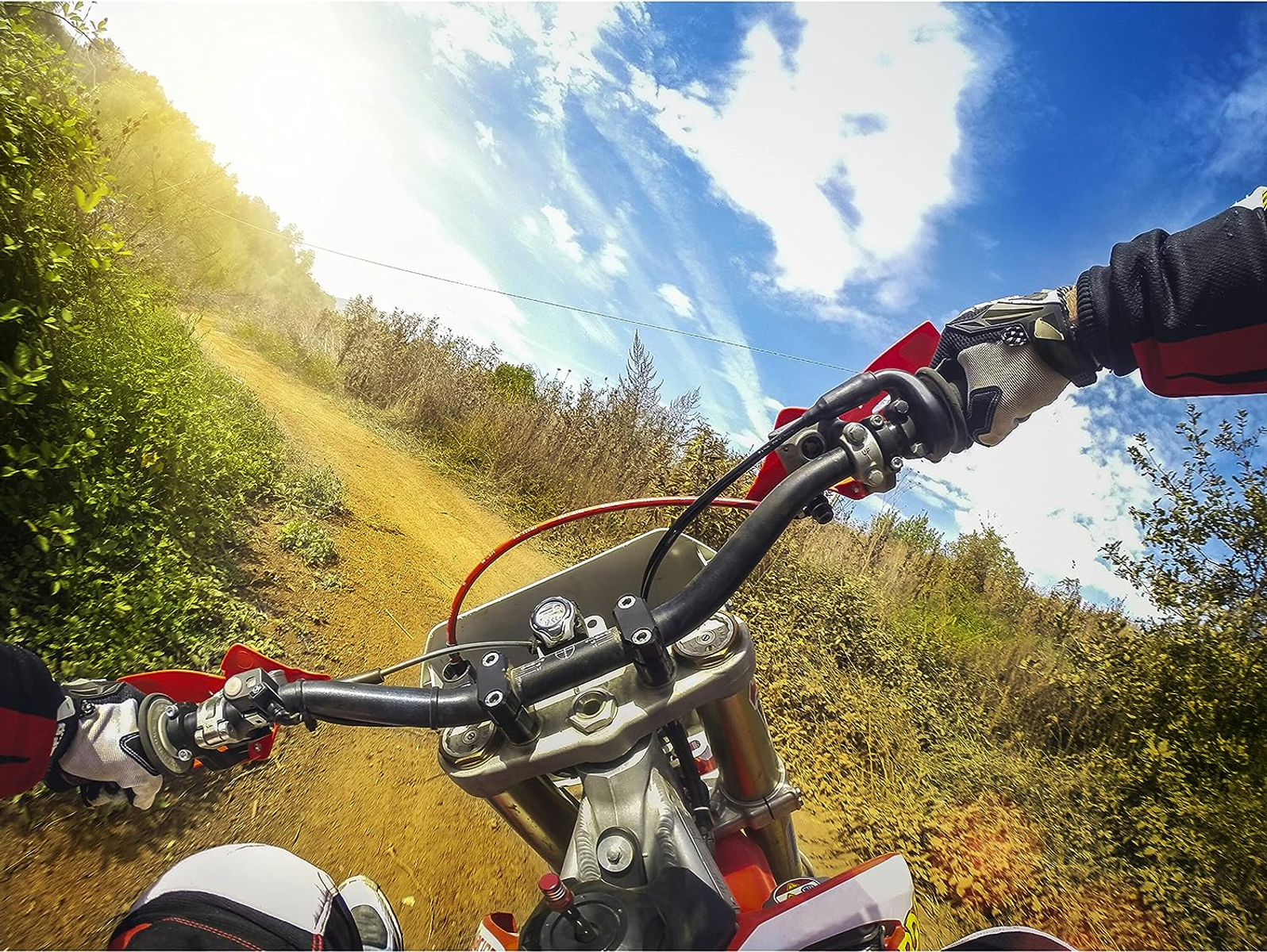 Ego-Perspektive einer Person, die mit einem Motocross-Motorrad auf einem Feldweg fährt. Der Himmel ist blau mit Wolken. Der Lenker ist sichtbar.