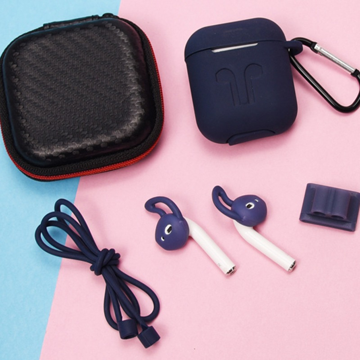 Disposición de accesorios tecnológicos: una funda, una funda para auriculares, dos auriculares, un soporte y un cable, todo sobre un fondo rosa y azul.