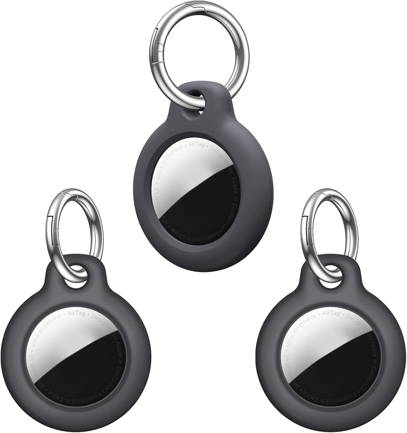 Drei Apple AirTags mit Schlüsselringen. Sie sind dunkelgrau mit einem silbernen und schwarzen kreisförmigen Design und einem silbernen Schlüsselring.