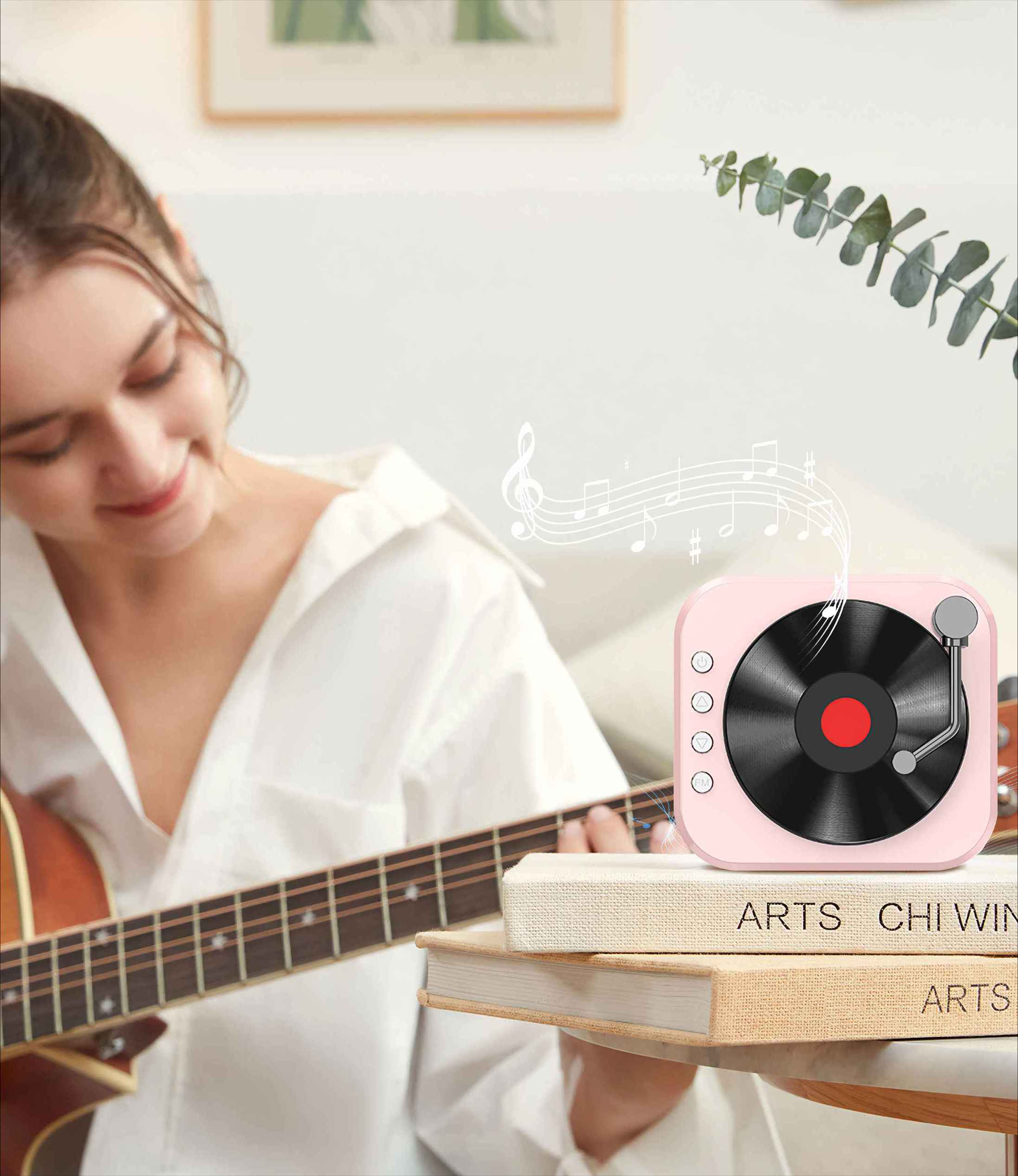 Frau spielt Gitarre, rosa Plattenspieler auf Büchern, Noten. Heller Hintergrund, Blätter rechts oben.